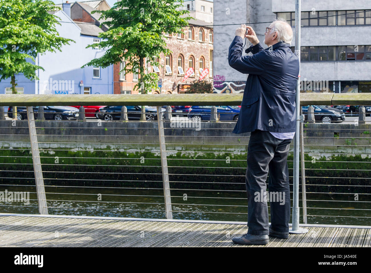 Tourist scatta una foto in piedi vicino al Fiume Lee su South Mall, Cork, Irlanda. Foto Stock