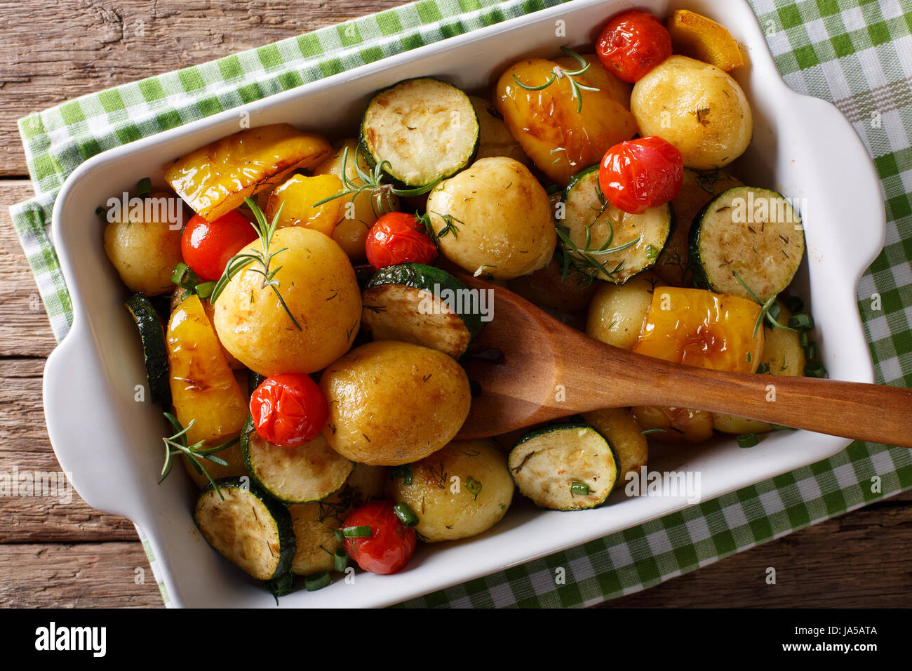 Cibo vegetariano: nuove patate al forno con zucchine, peperoni e pomodori vicino fino in una teglia. vista orizzontale dal di sopra Foto Stock