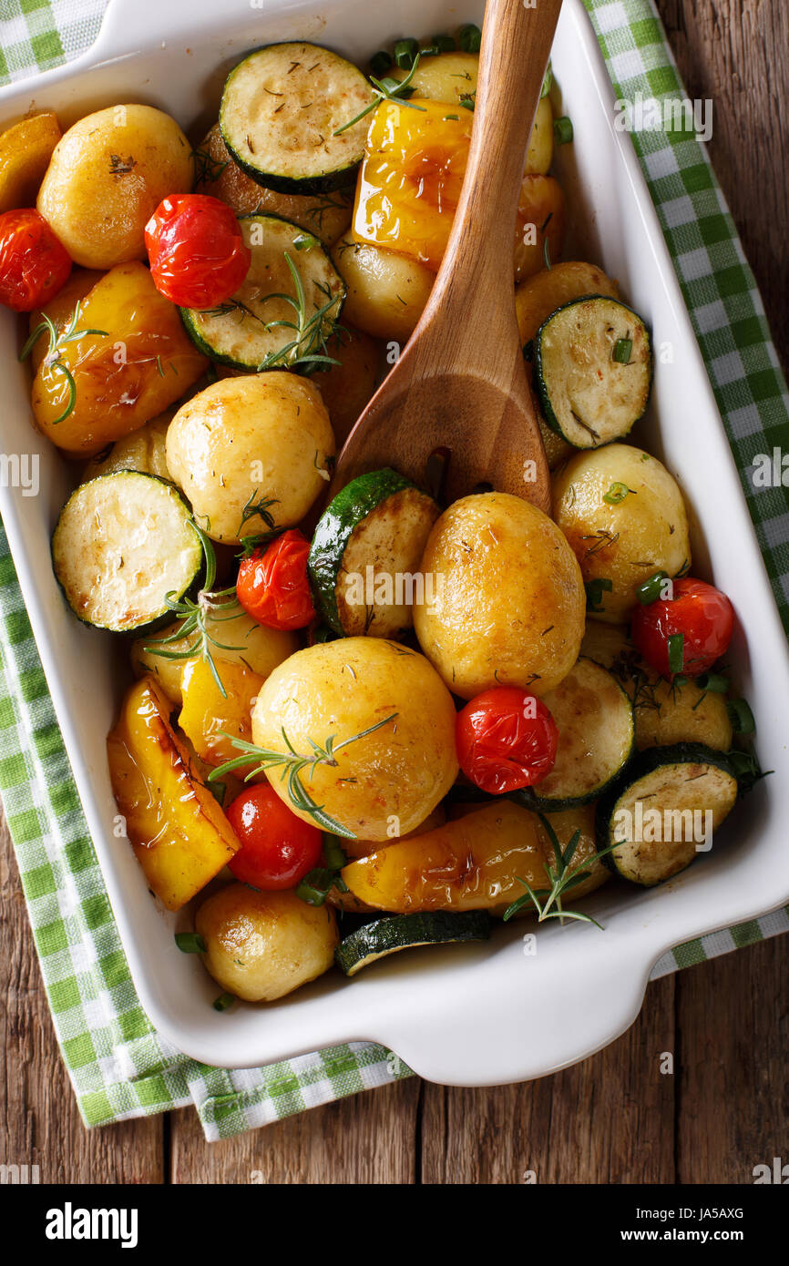 Cibo vegetariano: nuove patate al forno con zucchine, peperoni e pomodori vicino fino in una teglia. vista verticale da sopra Foto Stock