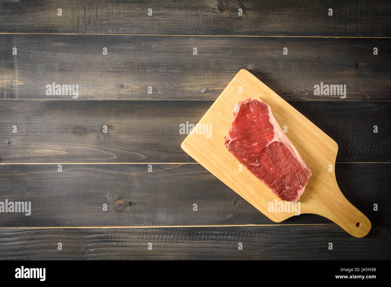 Materie di manzo bistecca di controfiletto su tagliere in legno, vista dall'alto e spazio di copia Foto Stock