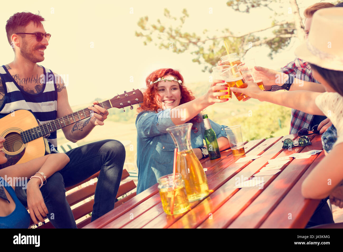 Allegro redhead toast femmina con gli amici con un bicchiere di birra in natura Foto Stock