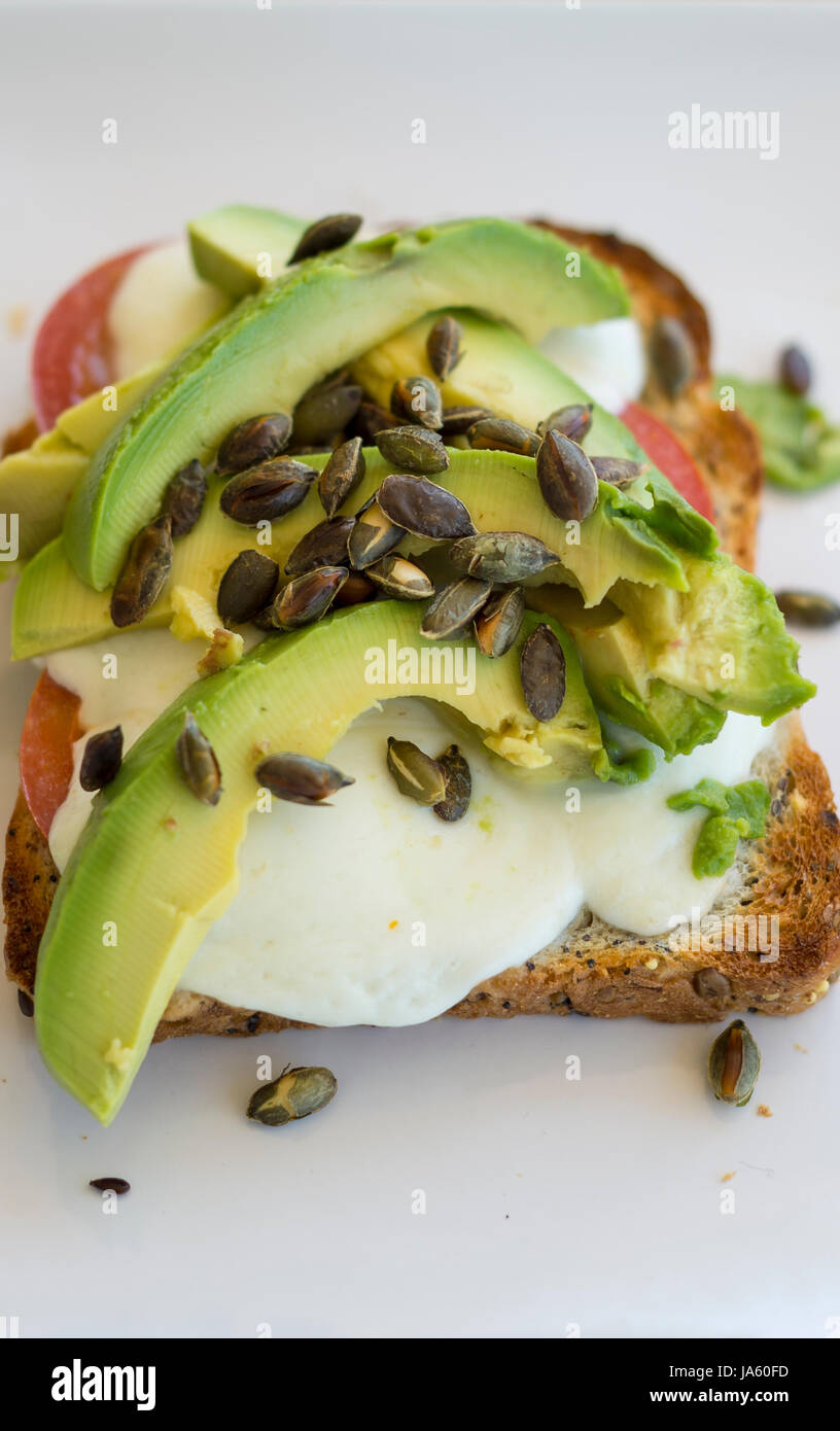 Avocado, mozzarella, pomodoro e tostati Semi di zucca su una fetta di pane tostato integrale Foto Stock