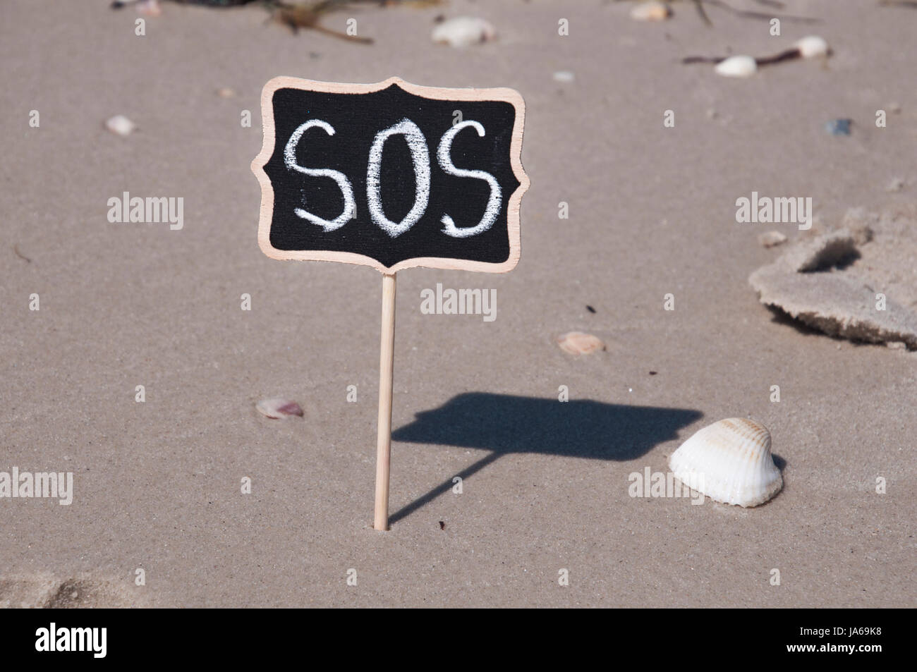 Targa di legno sulla spiaggia con una scritta SOS Foto Stock