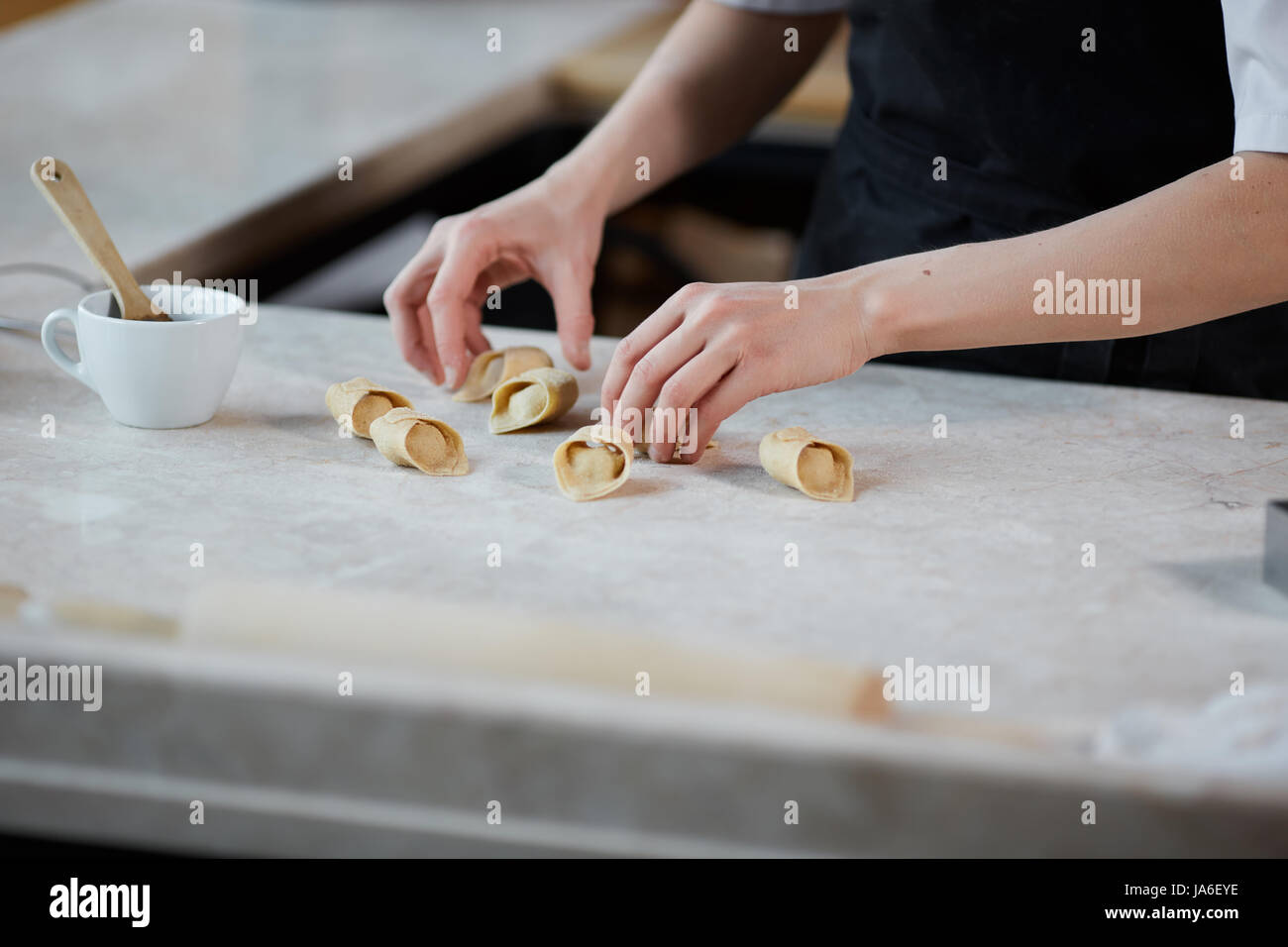 Interni orizzontali crop colpo di mani di donna che lavorano con impastare e formare la pasta in cucina. Foto Stock