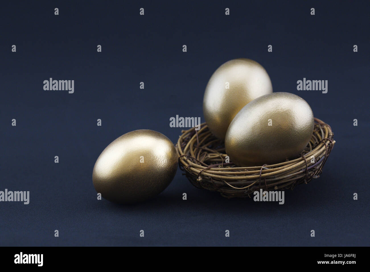 Sfondo nero aggiunge dramma al concetto di successo di tre, luccicanti oro nest uova. Copia di spazio disponibile sulla fotografia orizzontale. Foto Stock