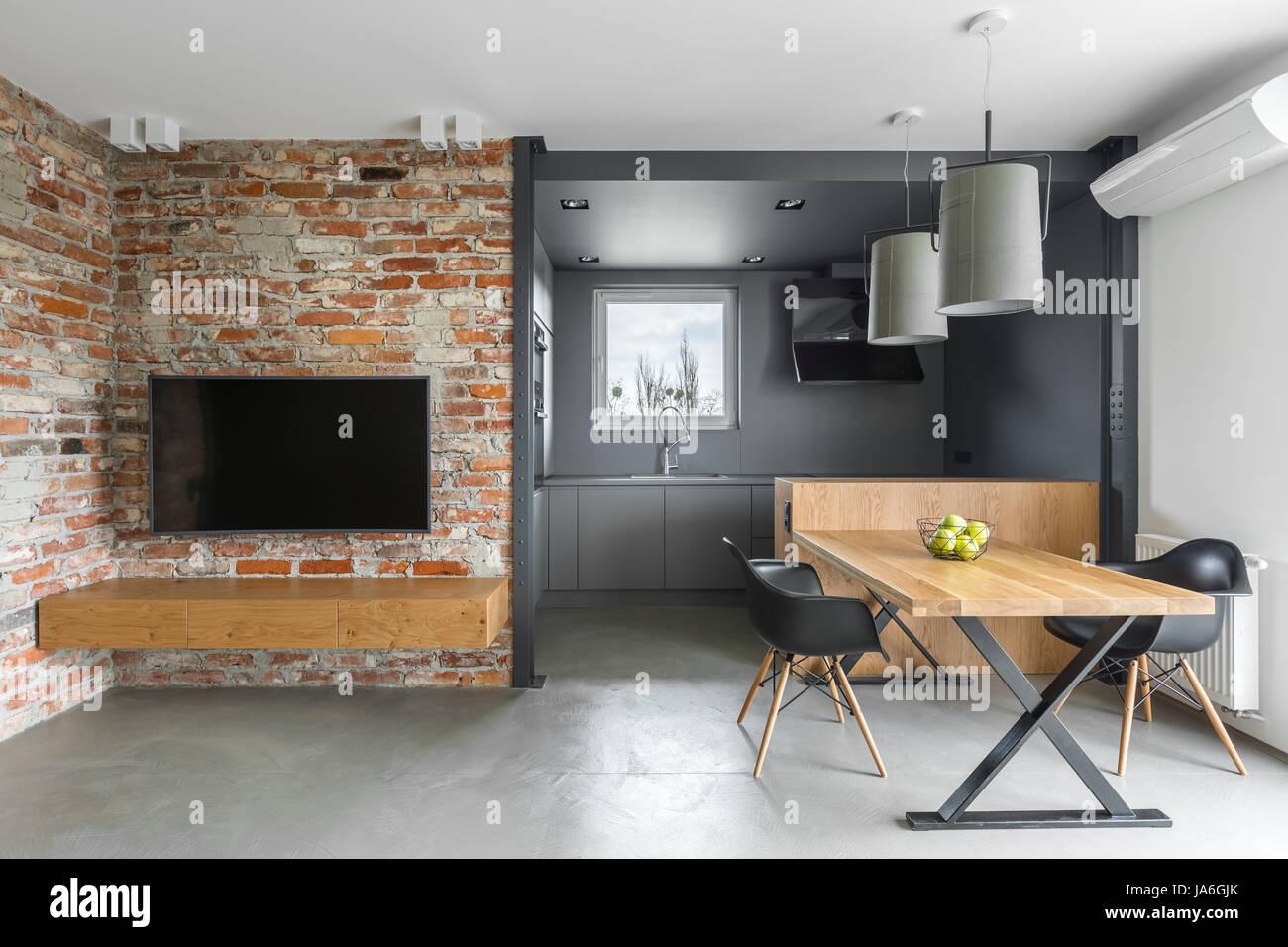 Stile industriale home interno con angolo cottura, TV, tavolo e sedie e un muro di mattoni Foto Stock