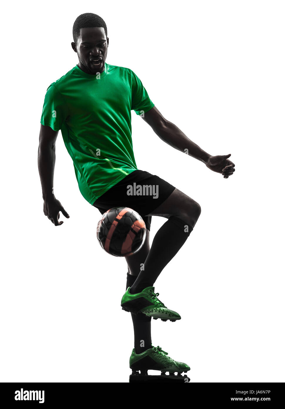 Un uomo africano giocatore di calcio maglia verde La giocoleria in silhouette su sfondo bianco Foto Stock