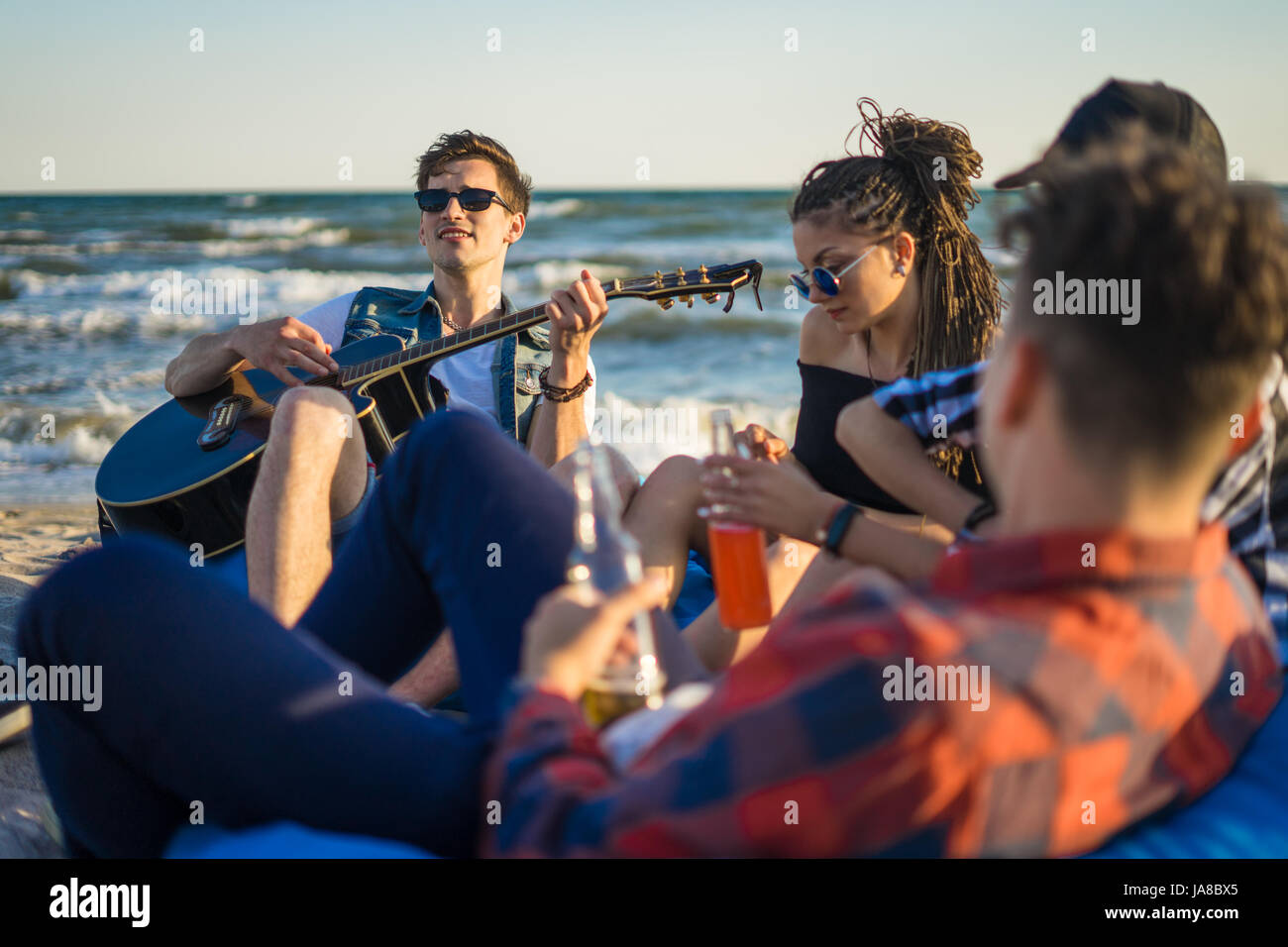 Il gruppo di amici con la chitarra e alcool sul beach party Foto Stock