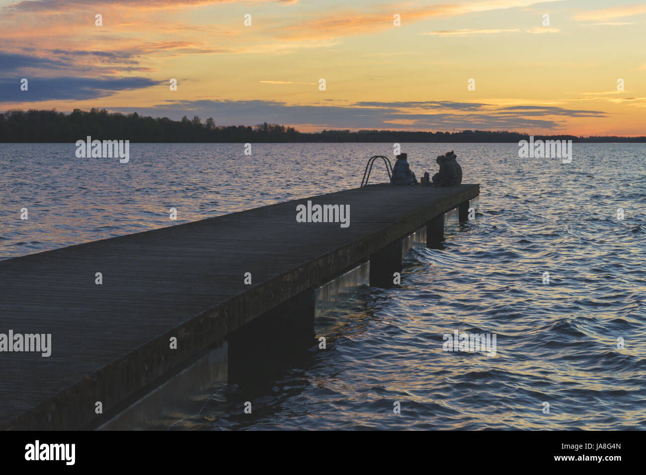 La gente non riconoscibile il relax sul lago di pier durante il bellissimo tramonto. Cielo romantico con le nuvole colorate Foto Stock