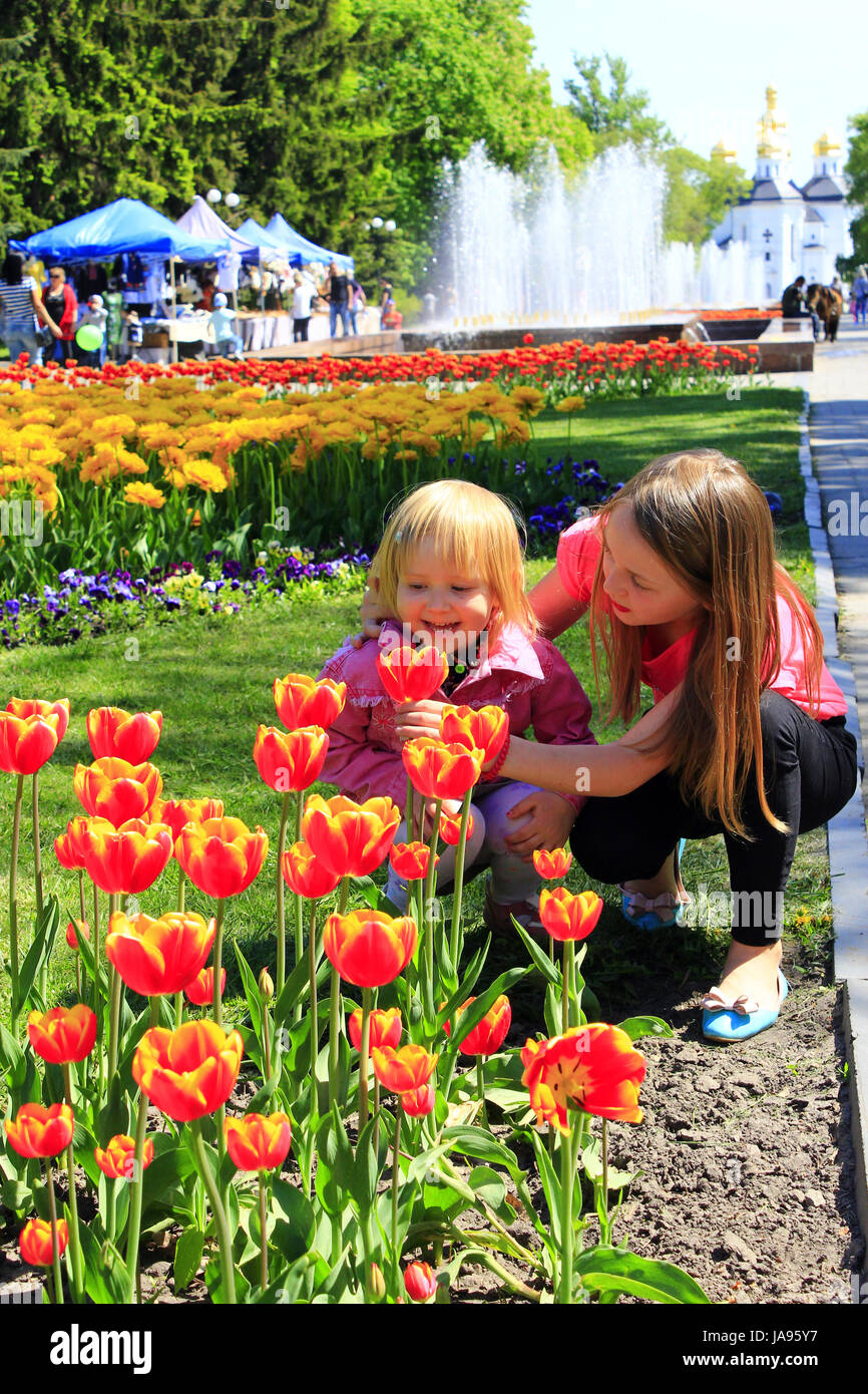 La sorella insegna il giovane di odore tulipani su una città aiuola. Bambini odore tulip su una città aiuola Foto Stock