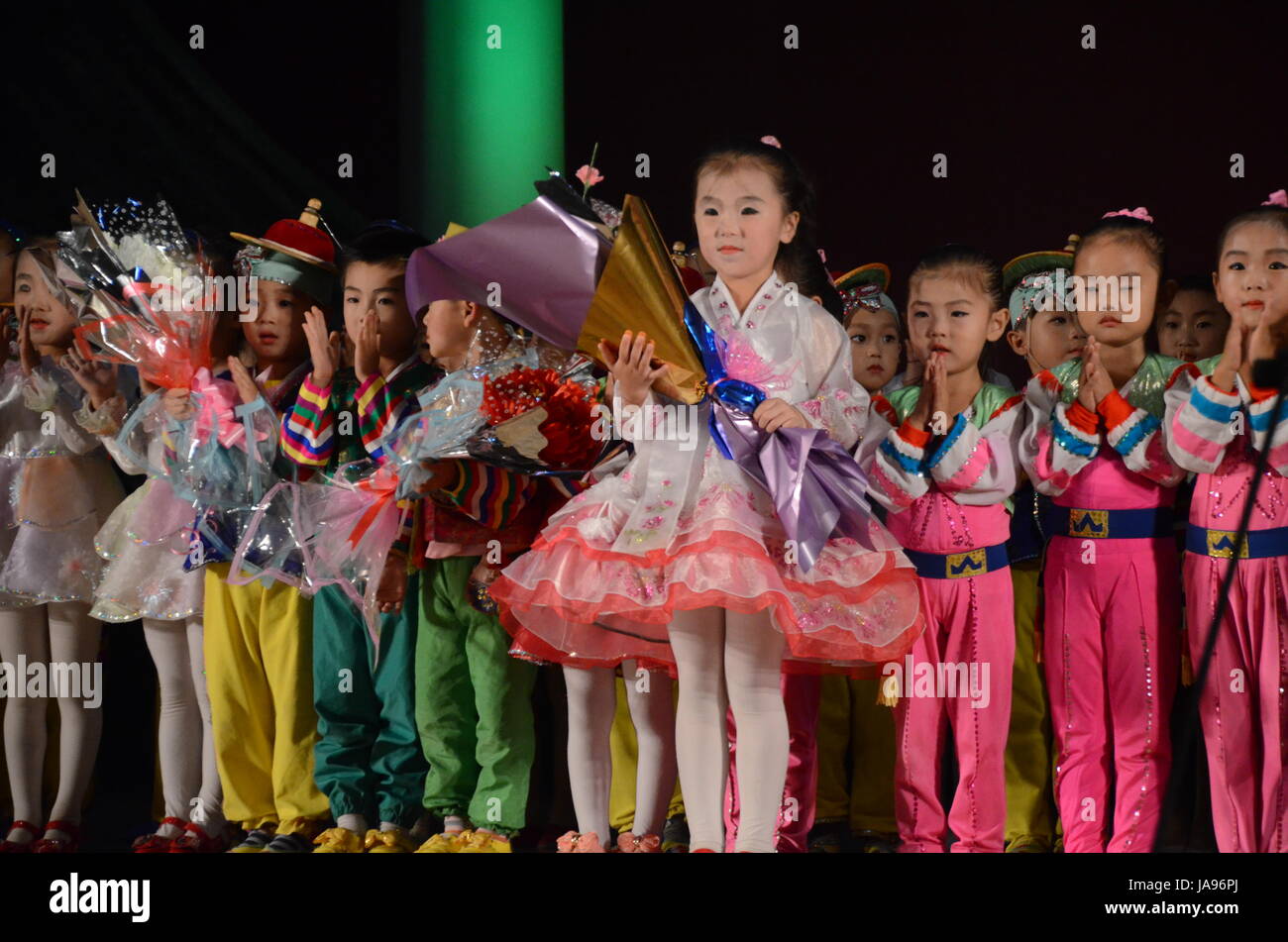 La Corea del Nord i bambini di eseguire musica e ballo nella città di Rason. Canzoni salutando il 'Grande' e 'Dear" leader Kim Il Sung e Kim Jong-Il. Foto Stock