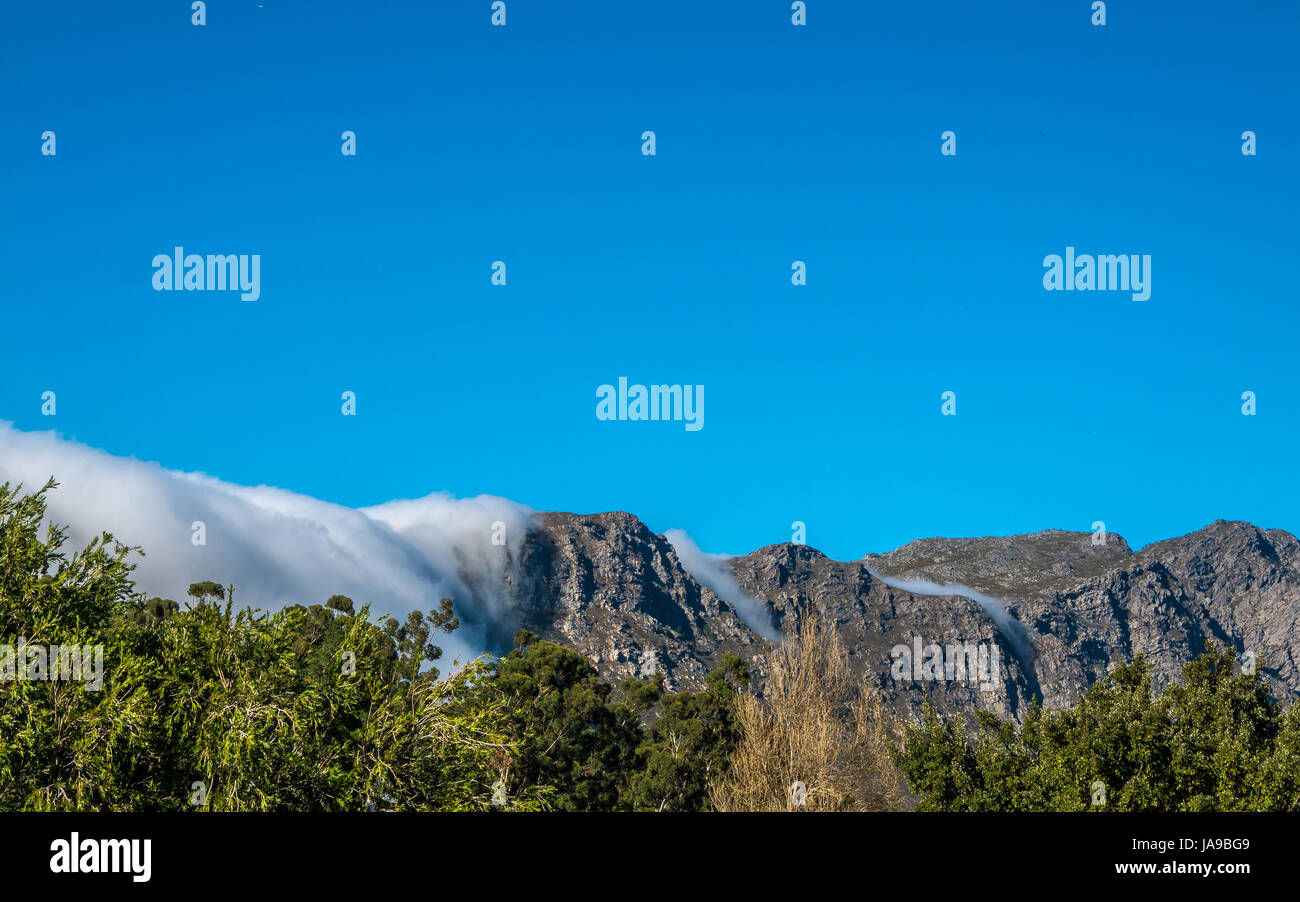 Nuvole il rotolamento su montagne come una cascata, con vigneto in primo piano, Franschhoek, Western Cape, Sud Africa Foto Stock