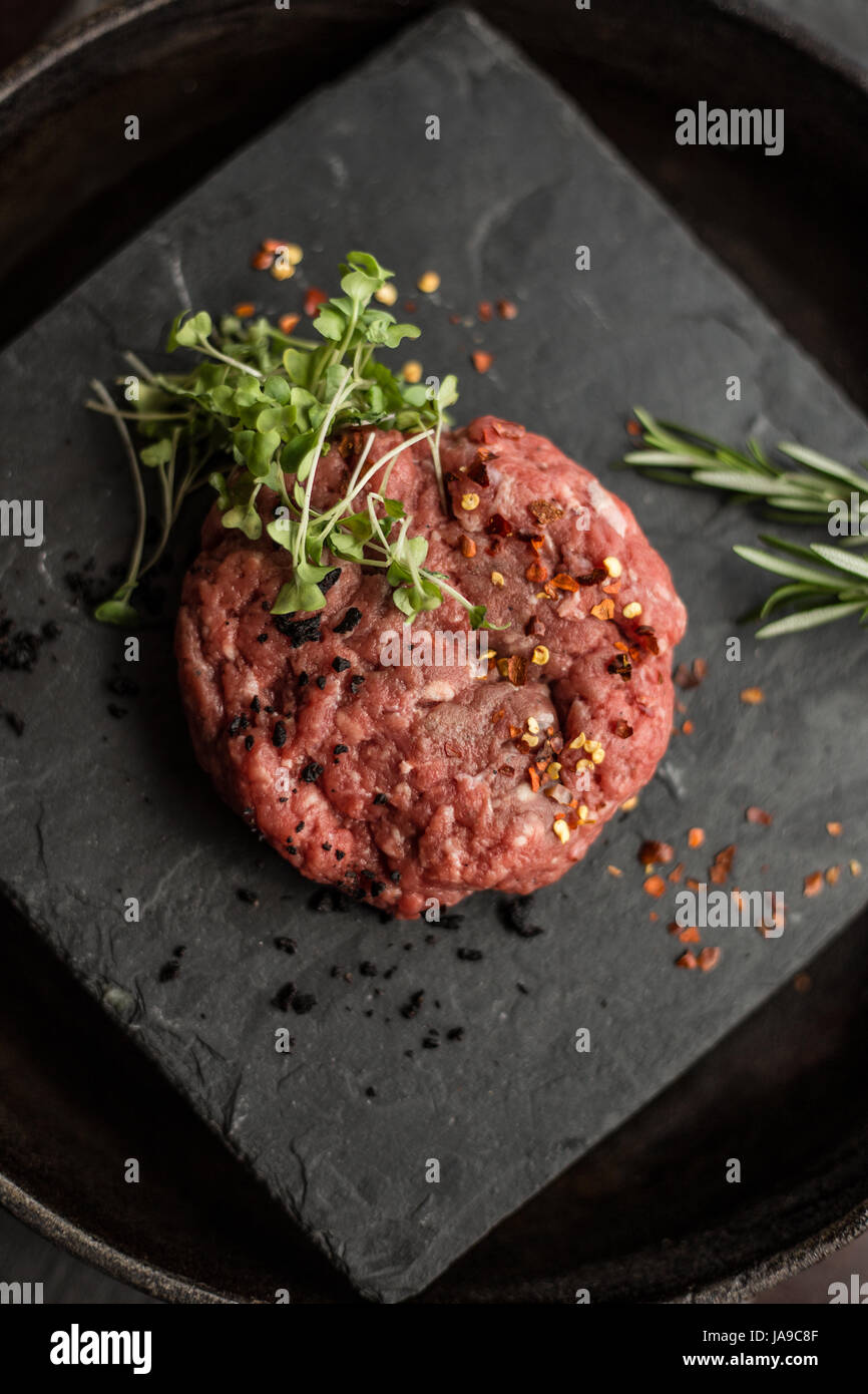 Terra cruda carne di manzo costolette di manzo con erbe e spezie sul bordo nero. Ristorante Foto Stock