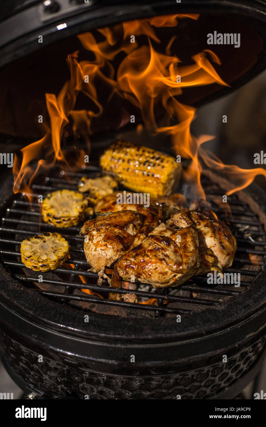 Grigliata di pollo intero con il mais su hot flaming grill. Barbecue. Ristorante Foto Stock