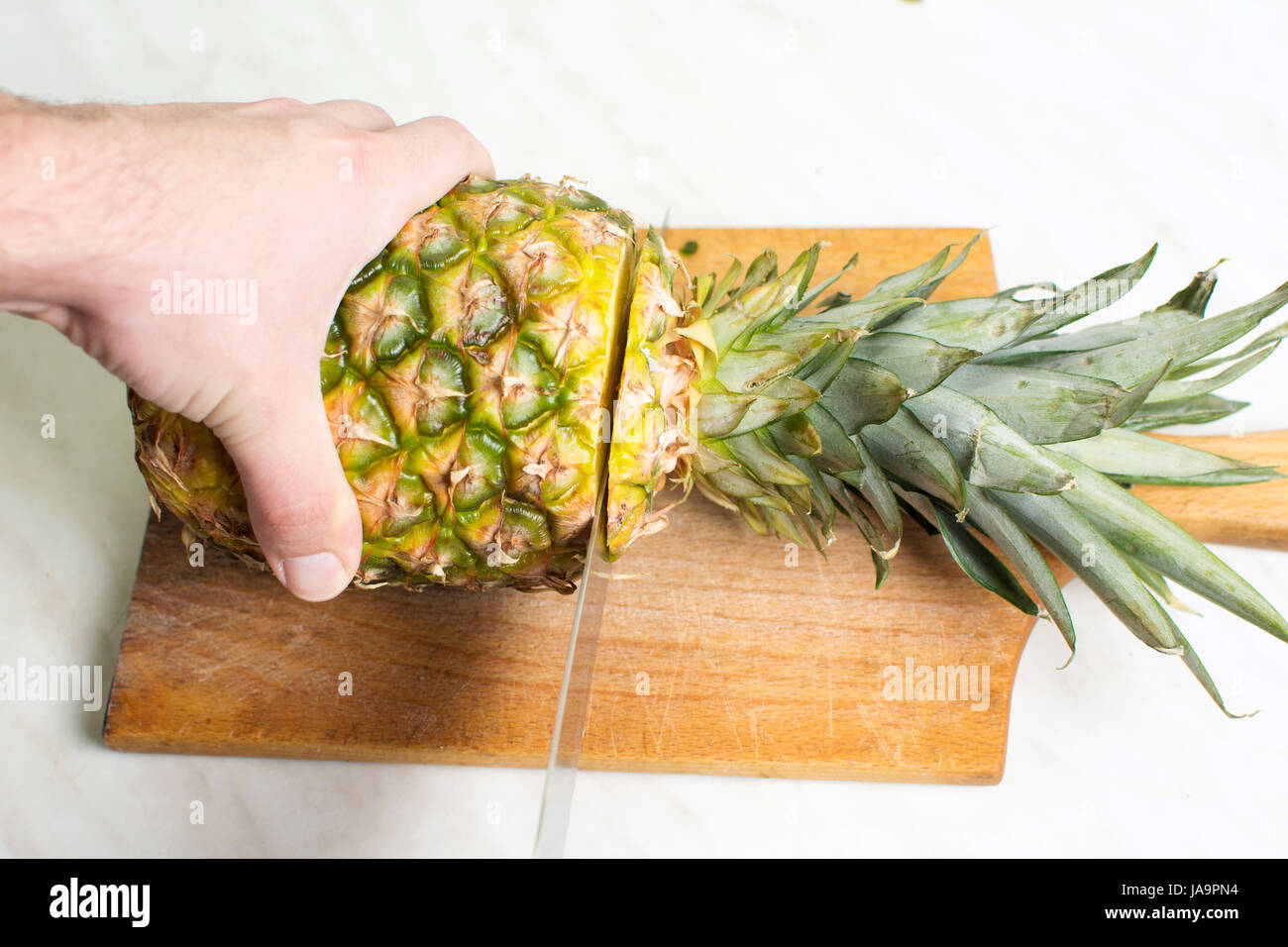 Uomo taglio di ananas frutta su una tavola di legno Foto Stock