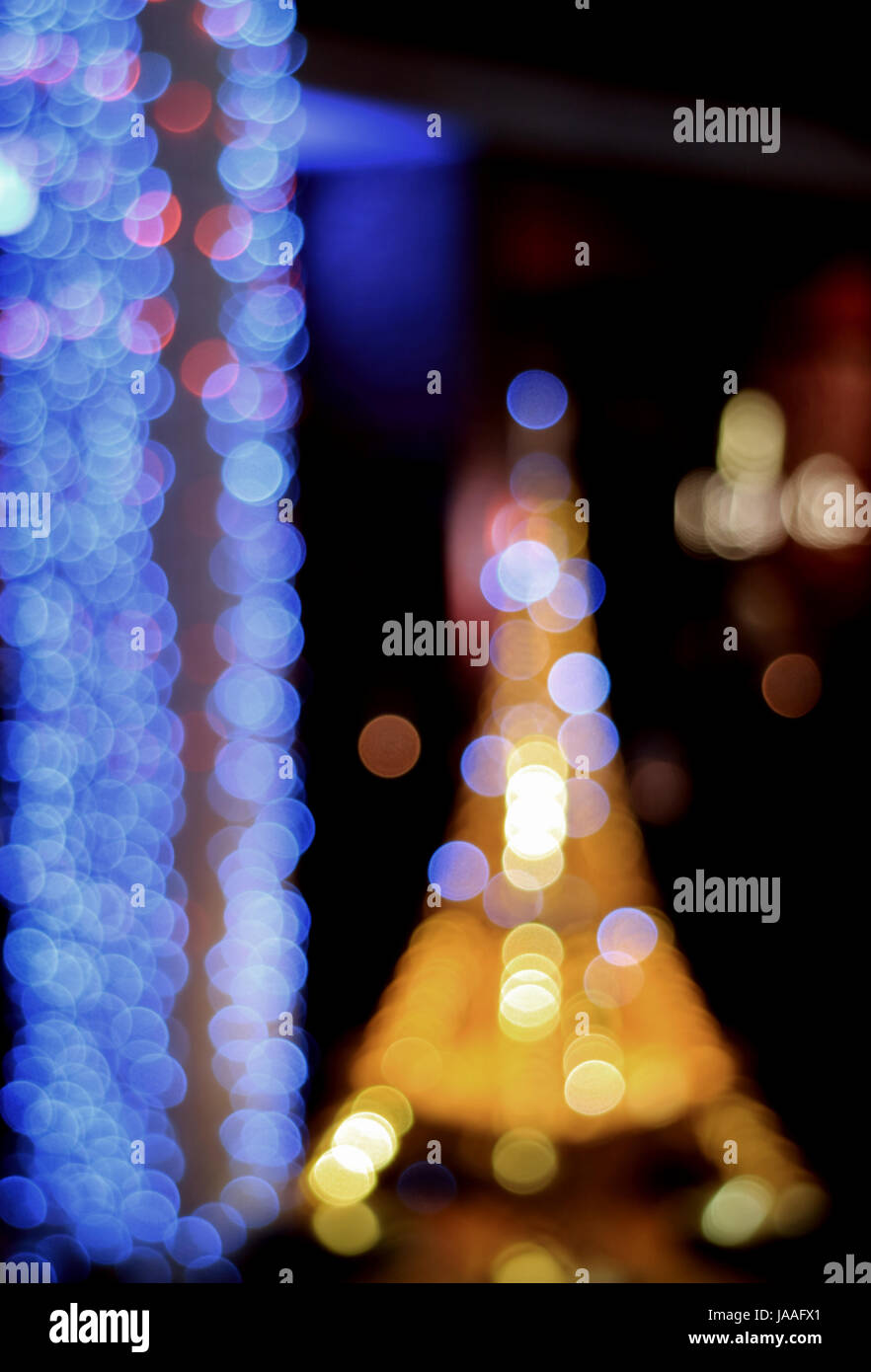 Al di fuori della messa a fuoco, offuscata, Bokeh, Defocalizzata blu e giallo luce in un giardino di notte, foto verticale per sfondo astratto Foto Stock