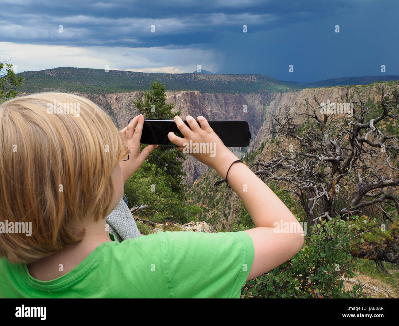 Un ragazzo è scattare una foto di un avvicinamento temporale con il suo smartphone al 'Black Canyon del Gunnison' Parco Nazionale (Colorado, USA). Foto Stock