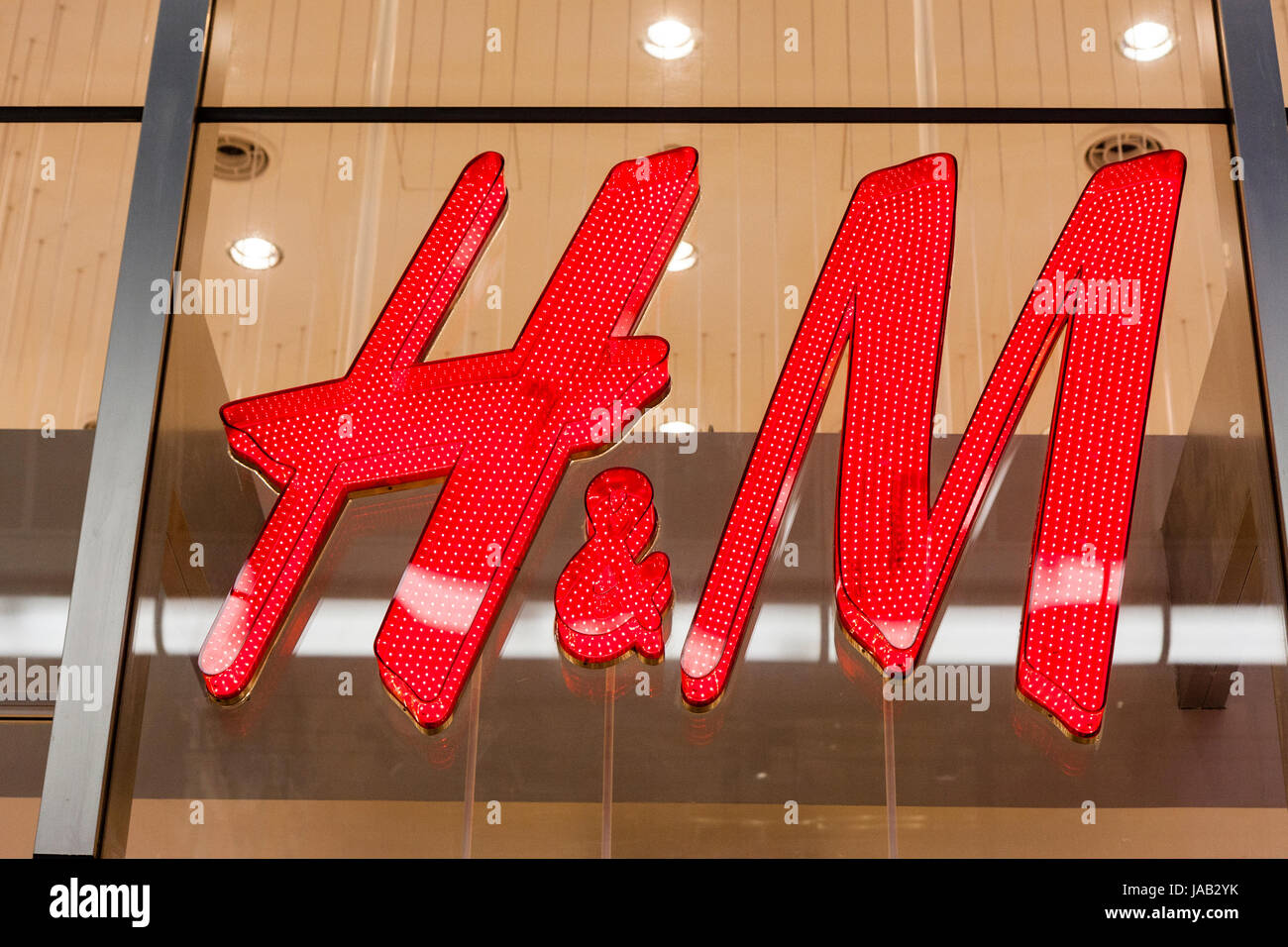 Giappone, Osaka, Shinsaibashi. Red H&M'insegna illuminata sul vetro anteriore del negozio. Foto Stock
