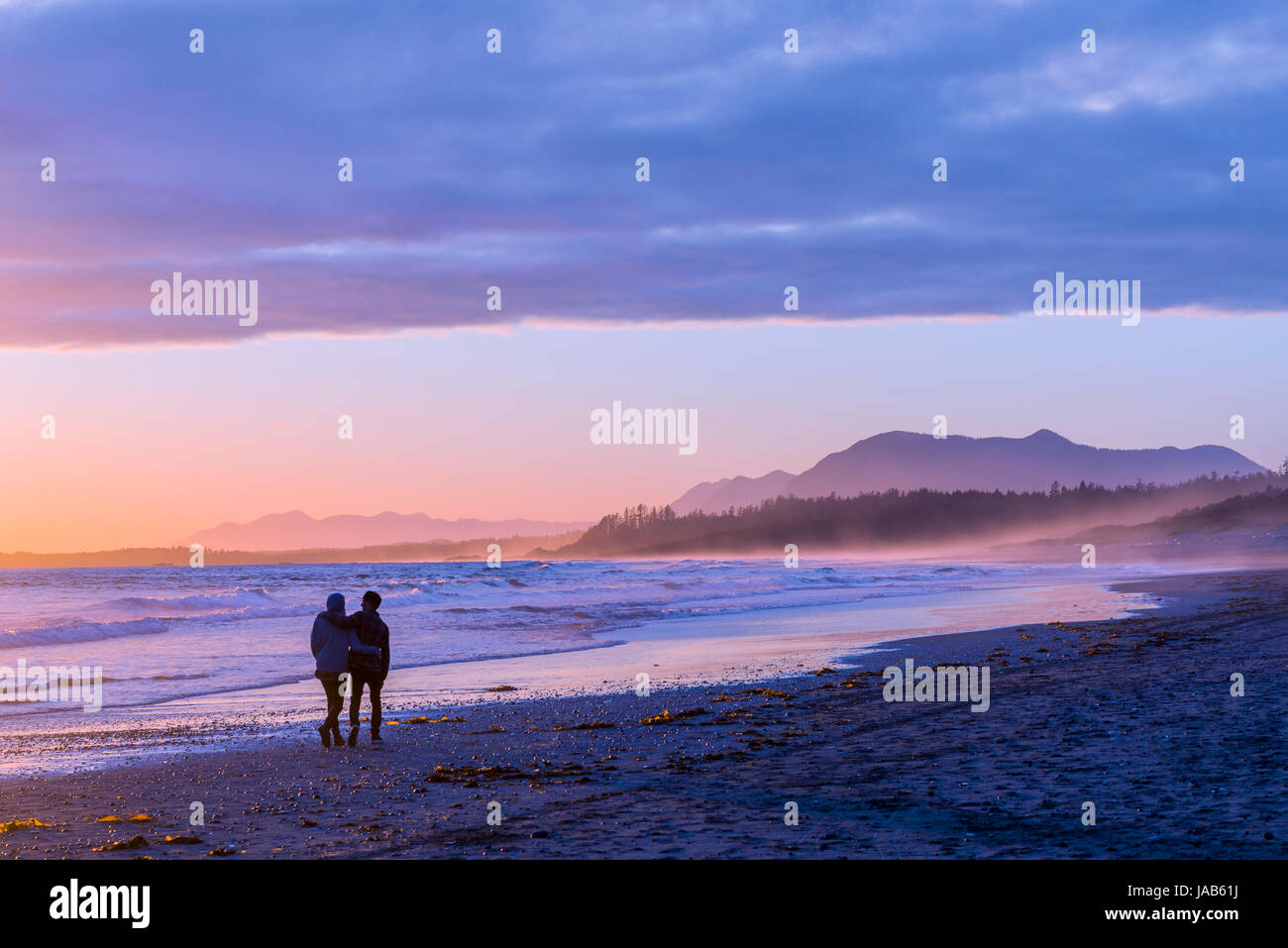 Un paio di passeggiata sulla lunga spiaggia al tramonto, Pacific Rim National Park, l'isola di Vancouver, British Columbia, Canada. Foto Stock