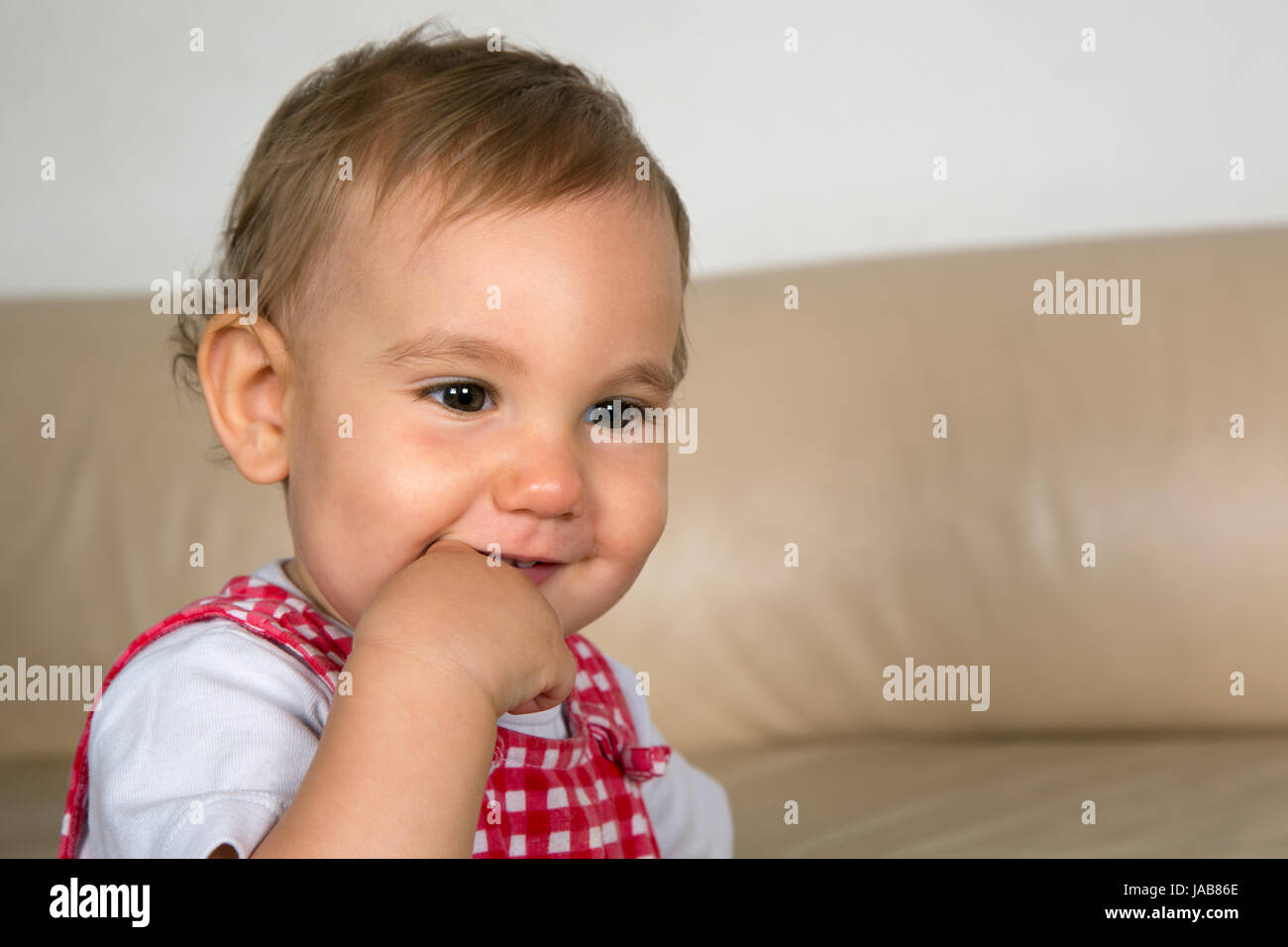 Ein lachendes Baby steckt seinen dito in den Mund Foto Stock