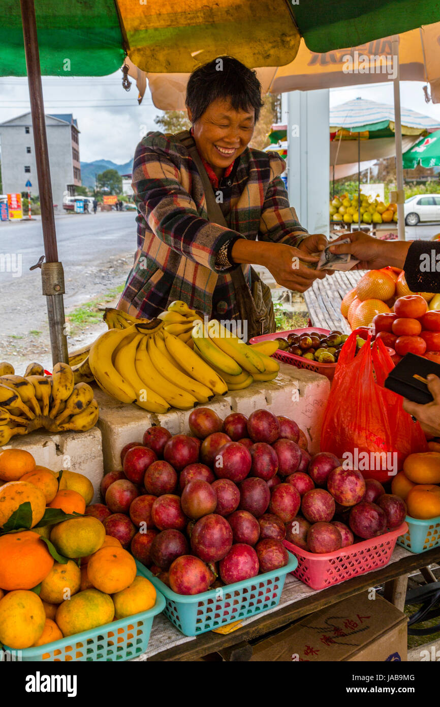 Nel Guangxi, Cina. Tra Yangshuo e Longji. Frutta Stand Venditore effettua una vendita. Foto Stock