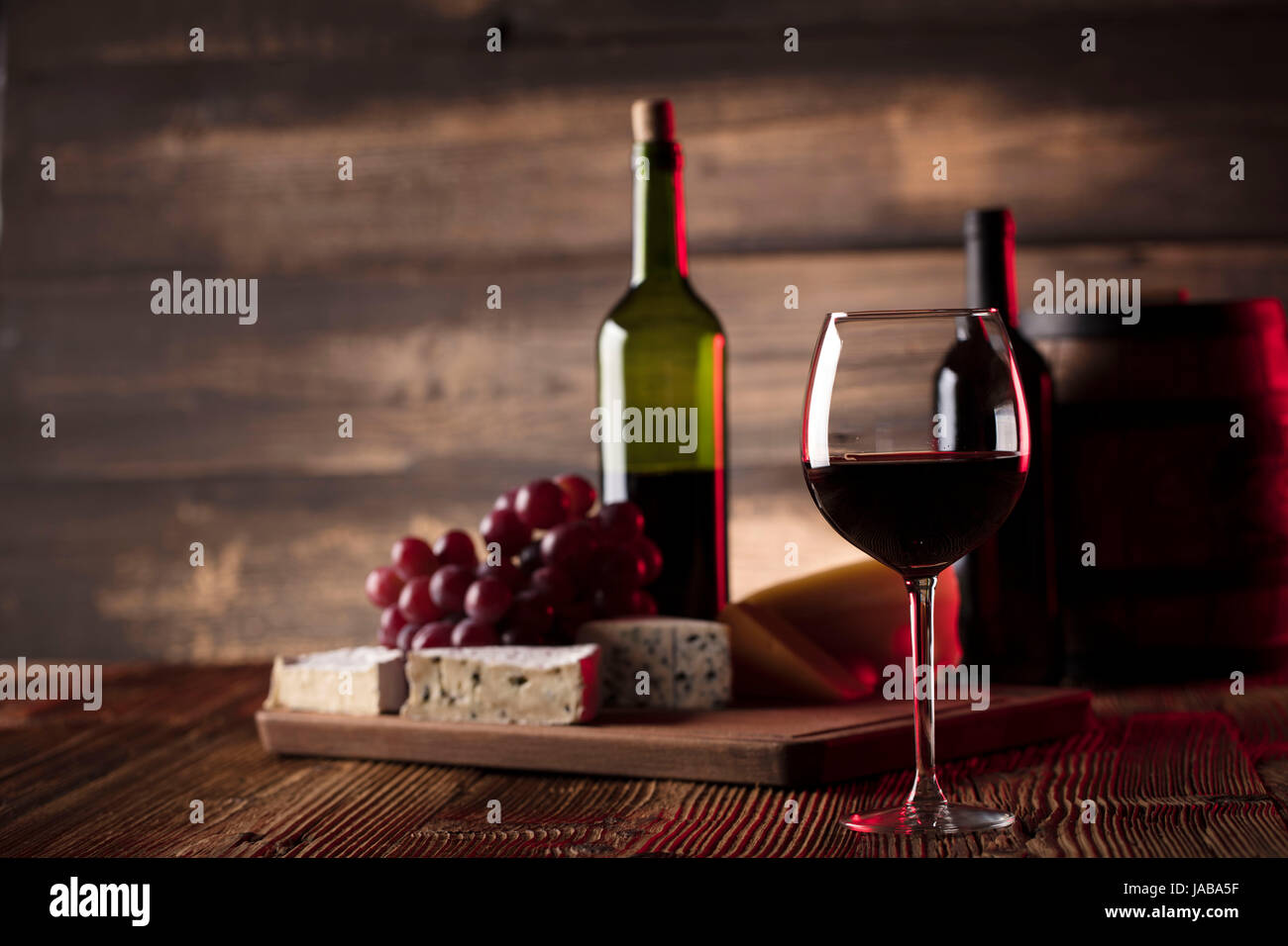 Bicchiere di vino rosso, formaggio e uva sul vecchio tavolo in legno. Vecchio sfondo di legno. Foto Stock