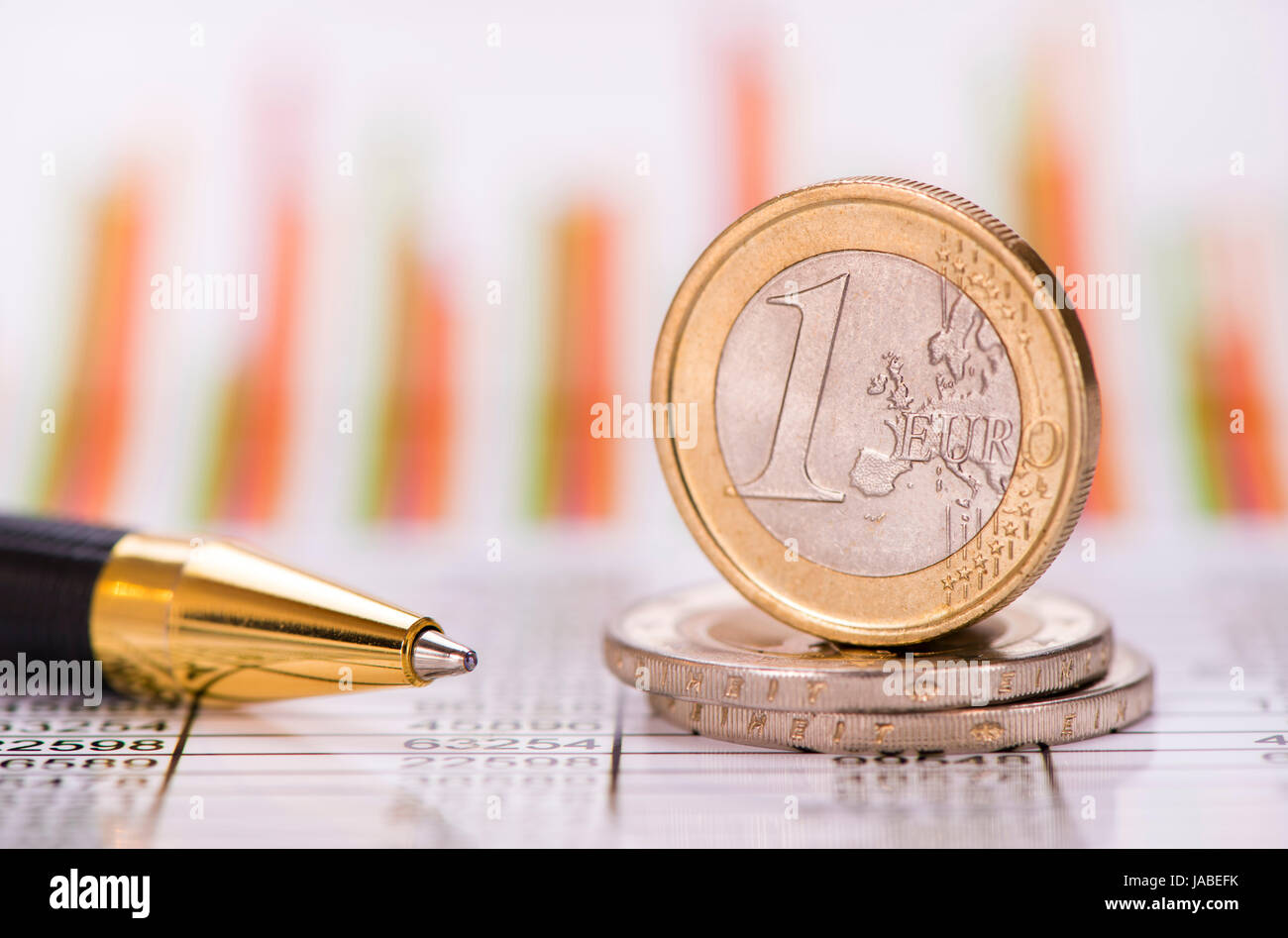 Impilati monete in euro sul foglio della tabella con il grafico del mercato dei cambi Foto Stock