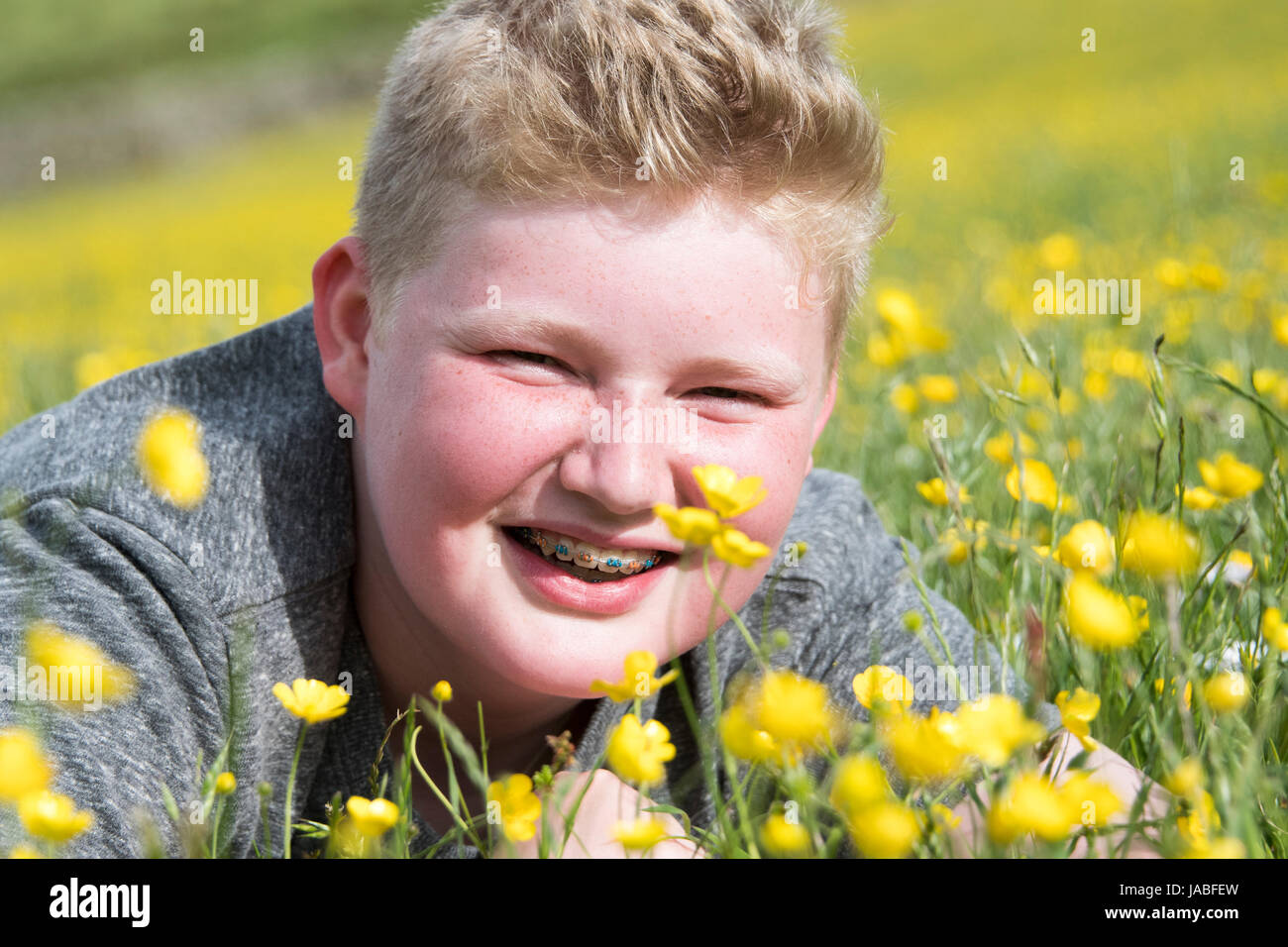 Sorridente boysat adolescente nel prato di fiori selvaggi, North Yorkshire, Regno Unito Foto Stock