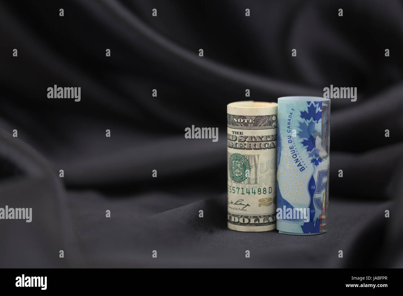 Alleati e solidale commercio partner relationship simboleggiato dal collocamento di americani e canadesi insieme denaro sul semplice, satin nero lo sfondo. Foto Stock