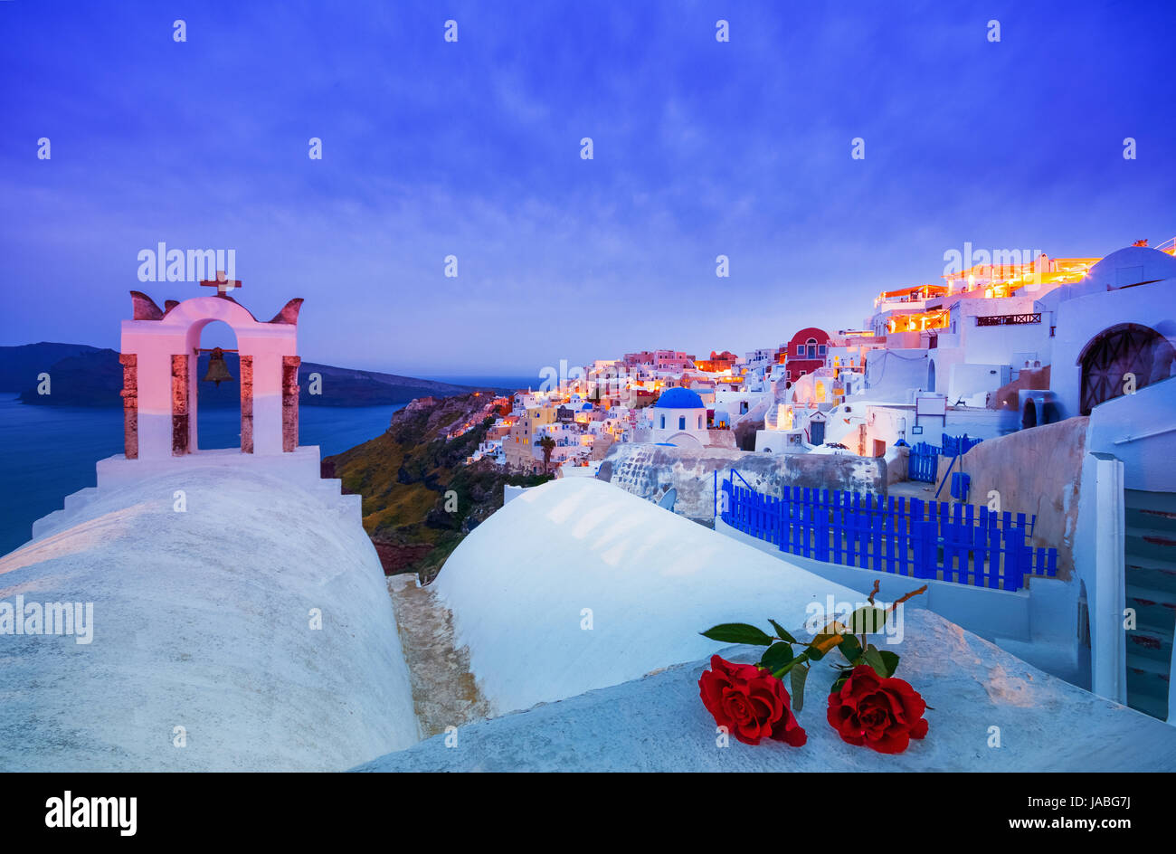 Il campanile di una chiesa ortodossa a Santorini con una coppia di rose rosse, Grecia. luna di miele estate egeo sullo sfondo delle Cicladi. Foto Stock