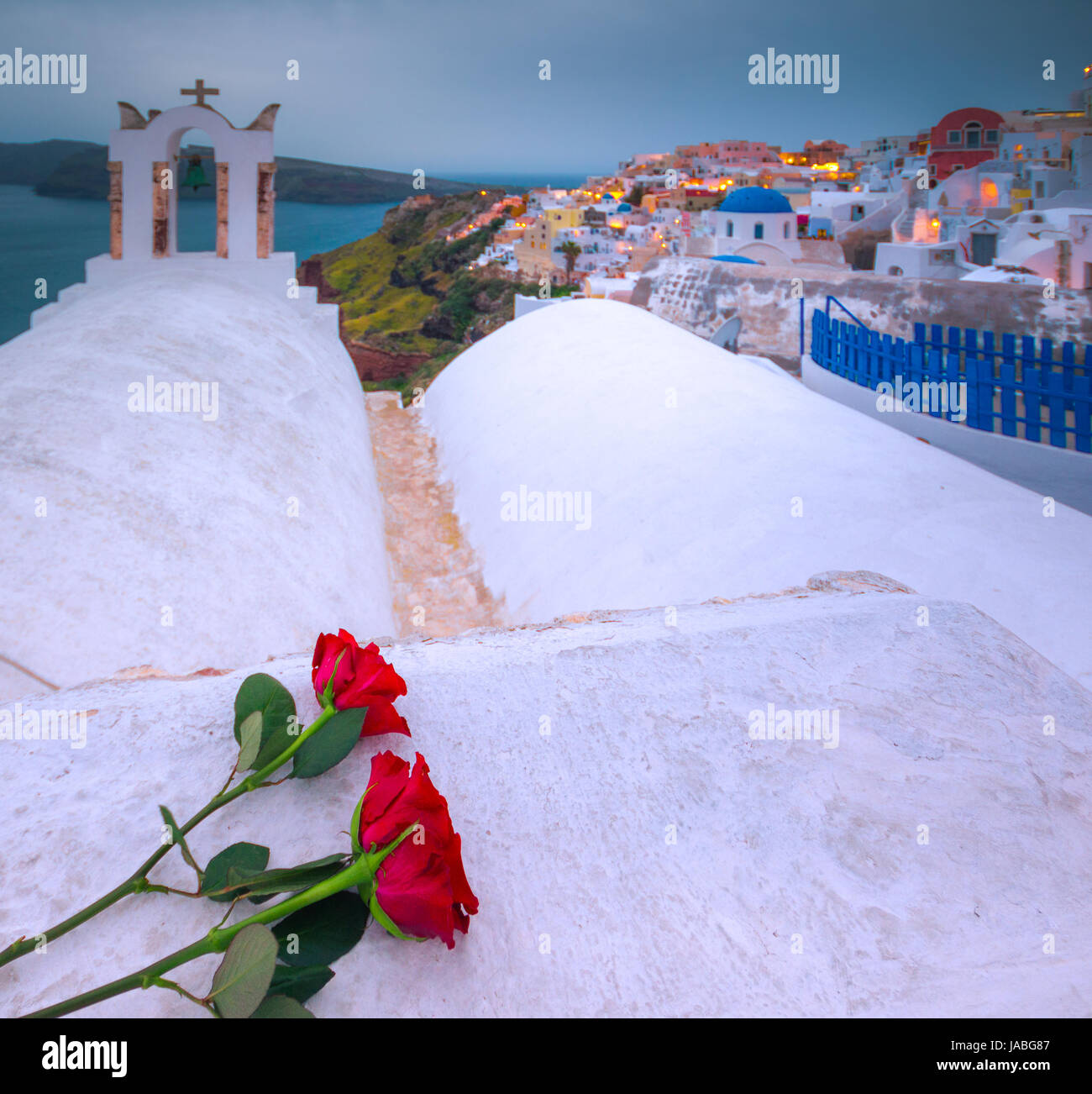 Il campanile di una chiesa ortodossa a Santorini con una coppia di rose rosse, Grecia. luna di miele estate egeo sullo sfondo delle Cicladi. Foto Stock