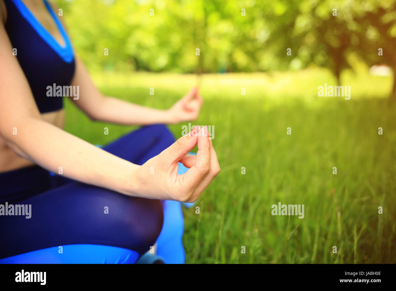 La meditazione sullo sfondo. Le mani della ragazza sportiva in lotos pongono close-up. Centro fitness esterno. Foto Stock
