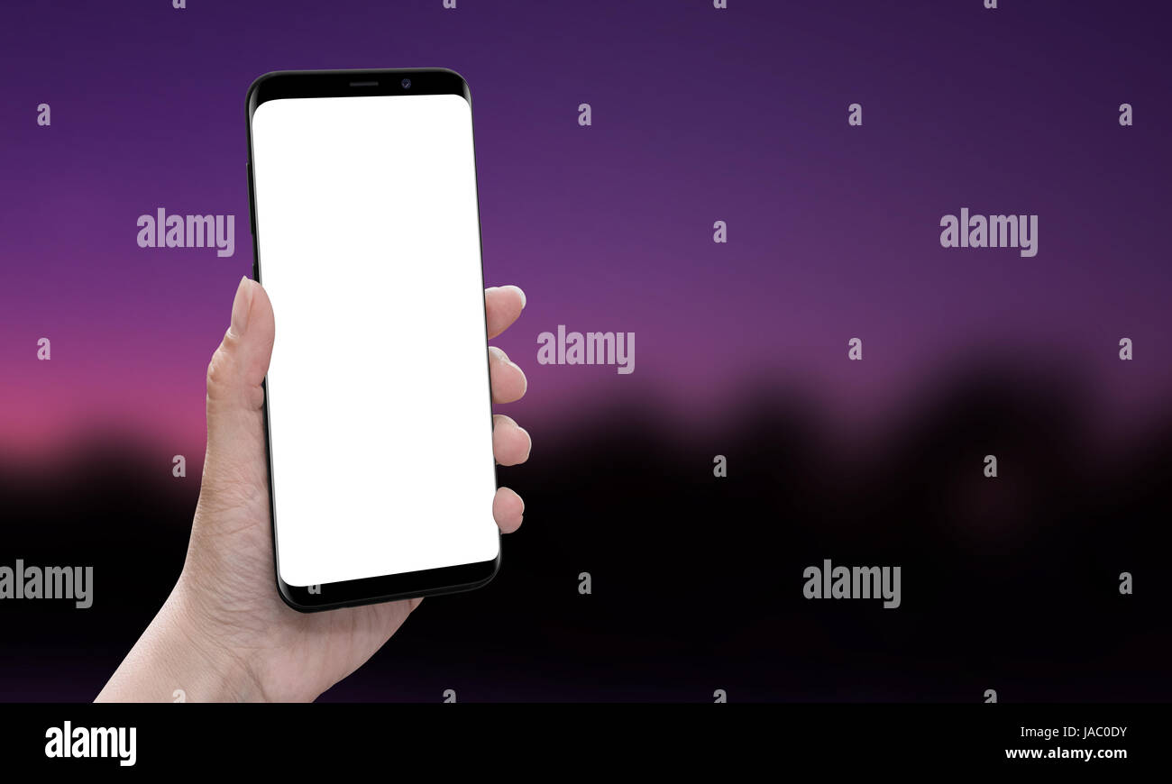 La mano che mostra moderne smart phone con bordi arrotondati. Isolato, schermo bianco per mockup, app, interfaccia utente web site, promozione del design. Backgrou sfocata Foto Stock
