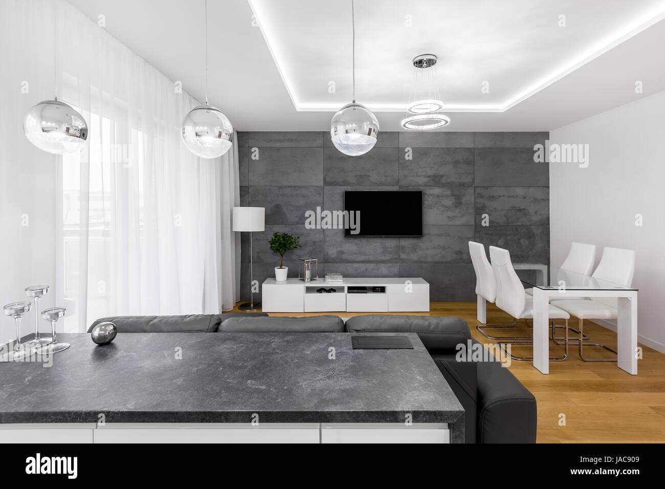 Moderna e piano aperto appartamento con parete in cemento, lampade, TV, tavolo e sedie Foto Stock