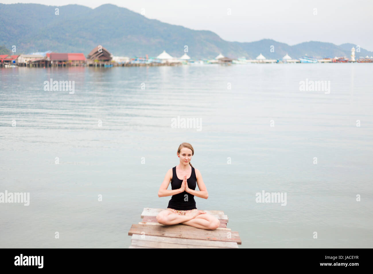 Estate sessione di yoga su un molo - Koh Chang Bang Bao fisherman village, Meditazione - lotus posano con namaste - padma asana. Attività nel sud est asiatico Foto Stock