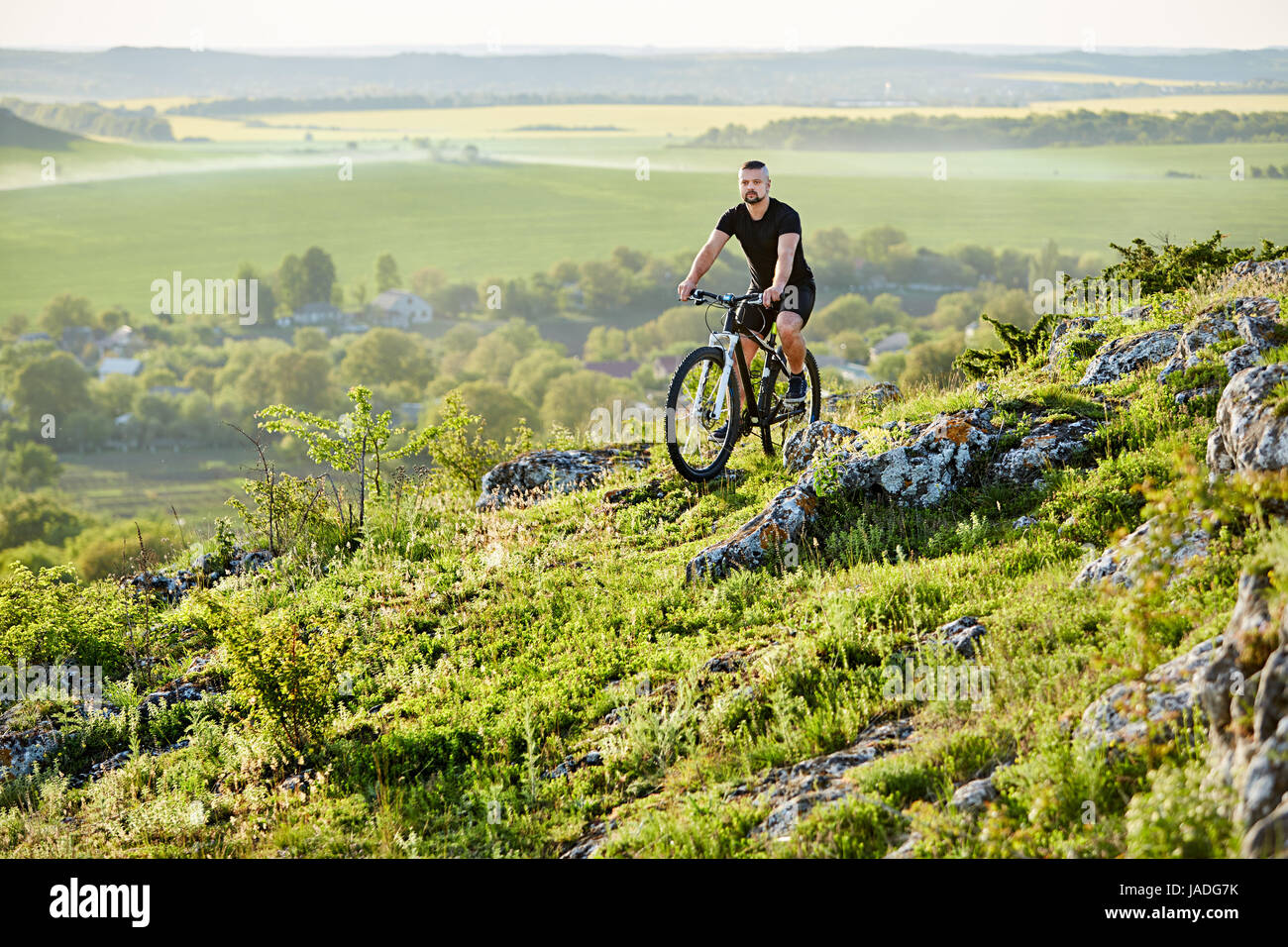 Giovane ciclista in sella alla bicicletta su un sentiero roccioso contro il bellissimo paesaggio. Foto Stock