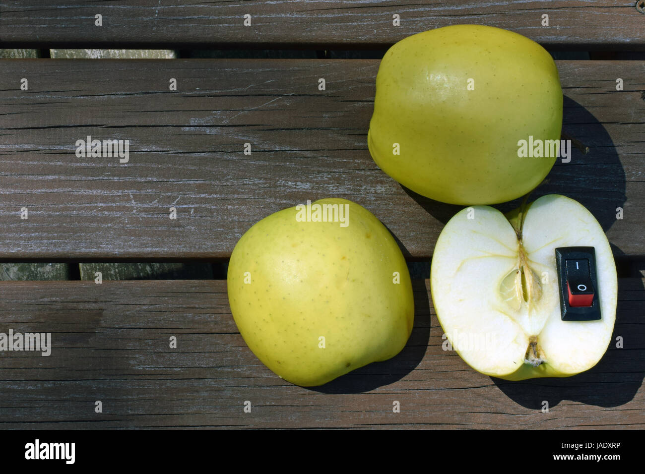 Tabella vista dall'alto di mele. Interruttore di alimentazione inserita a metà del frutto. Cibo sano e uno stile di vita più sano concetto Foto Stock