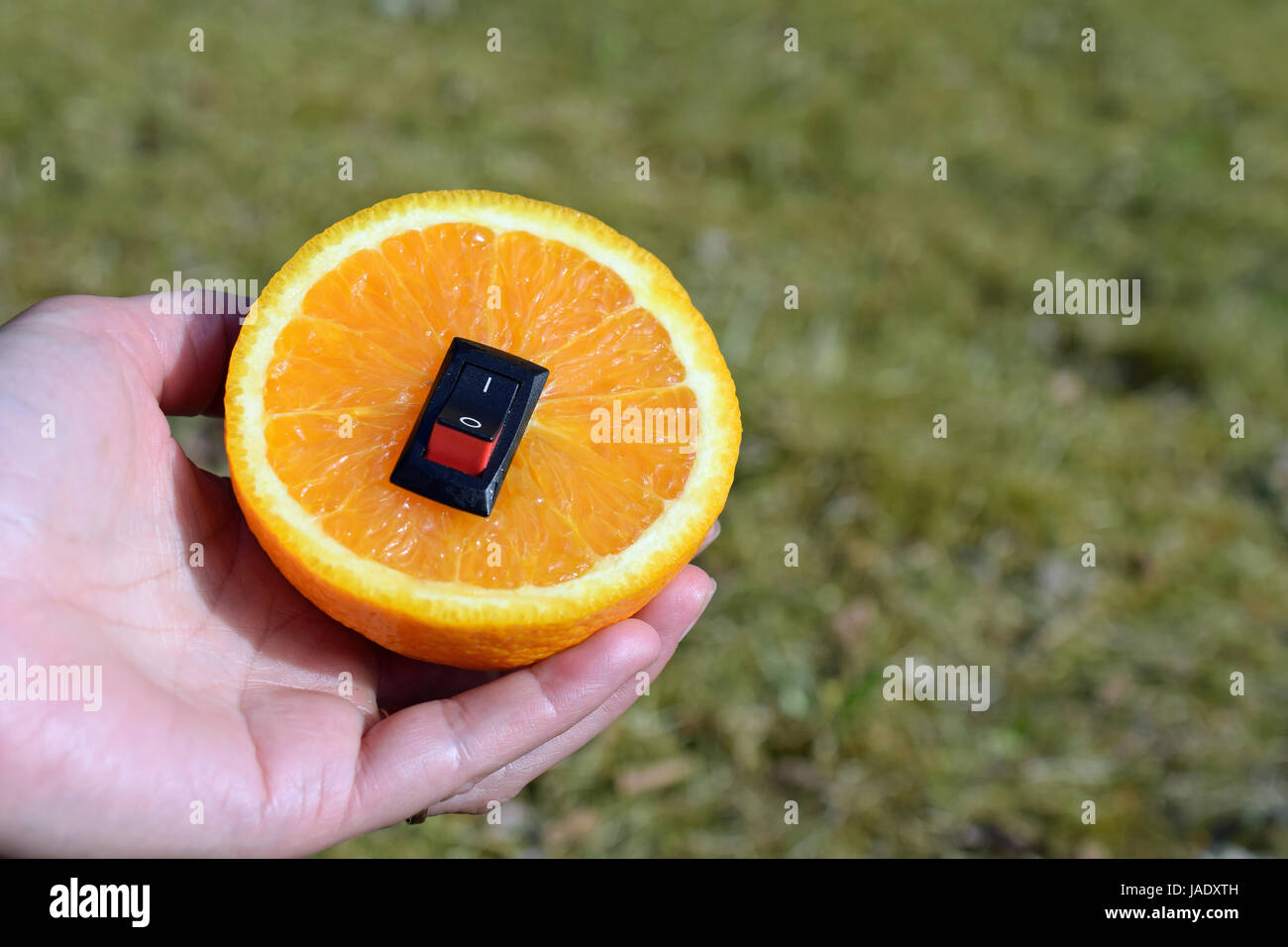 Unico cibo sano concetto. Donna mano che tiene una piastra con juicy orange con inserito un interruttore di alimentazione nel senso di un cambiamento di vita più sana. Foto Stock
