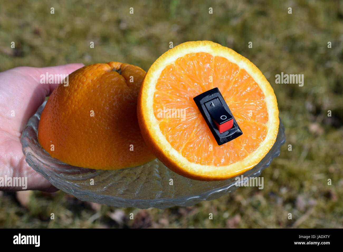 Unico cibo sano concetto. Donna mano che tiene una piastra con juicy orange con inserito un interruttore di alimentazione nel senso di un cambiamento di vita più sana. Foto Stock