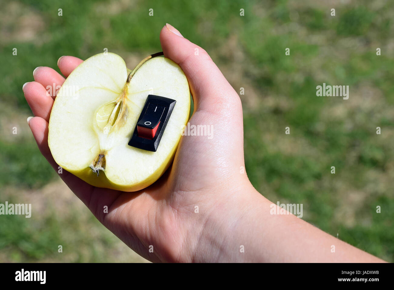 Unico cibo sano concetto. Mano azienda apple con inserito un interruttore di alimentazione nel senso di un cambiamento di vita più sana. Foto Stock