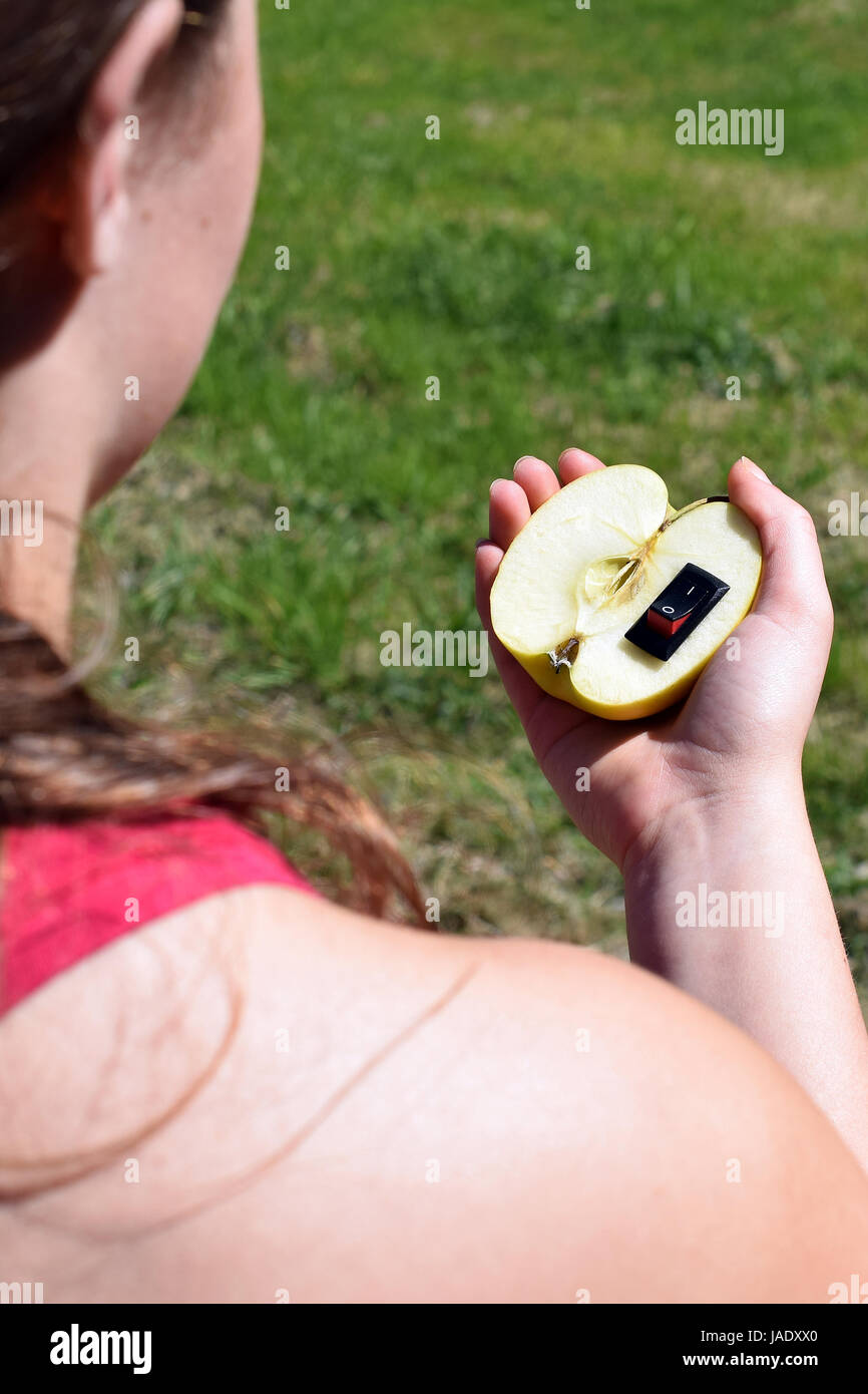 Unico cibo sano concetto. Mano azienda apple con inserito un interruttore di alimentazione nel senso di un cambiamento di vita più sana. Foto Stock