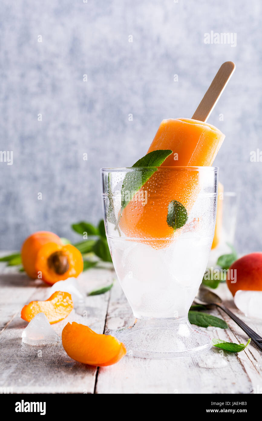 In casa albicocca popsicles nel bicchiere con ghiaccio e frutta albicocca. Estate concetto alimentare con copia spazio per il testo. Foto Stock