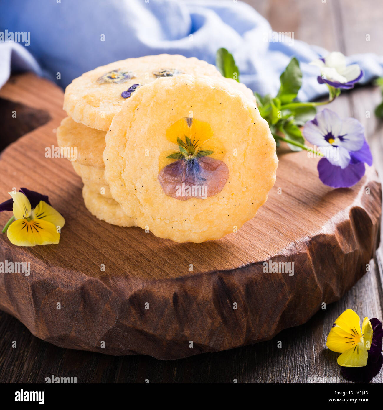 In casa biscotti frollini con fiori commestibili sul vecchio sfondo di legno. Cibo per le vacanze Foto Stock
