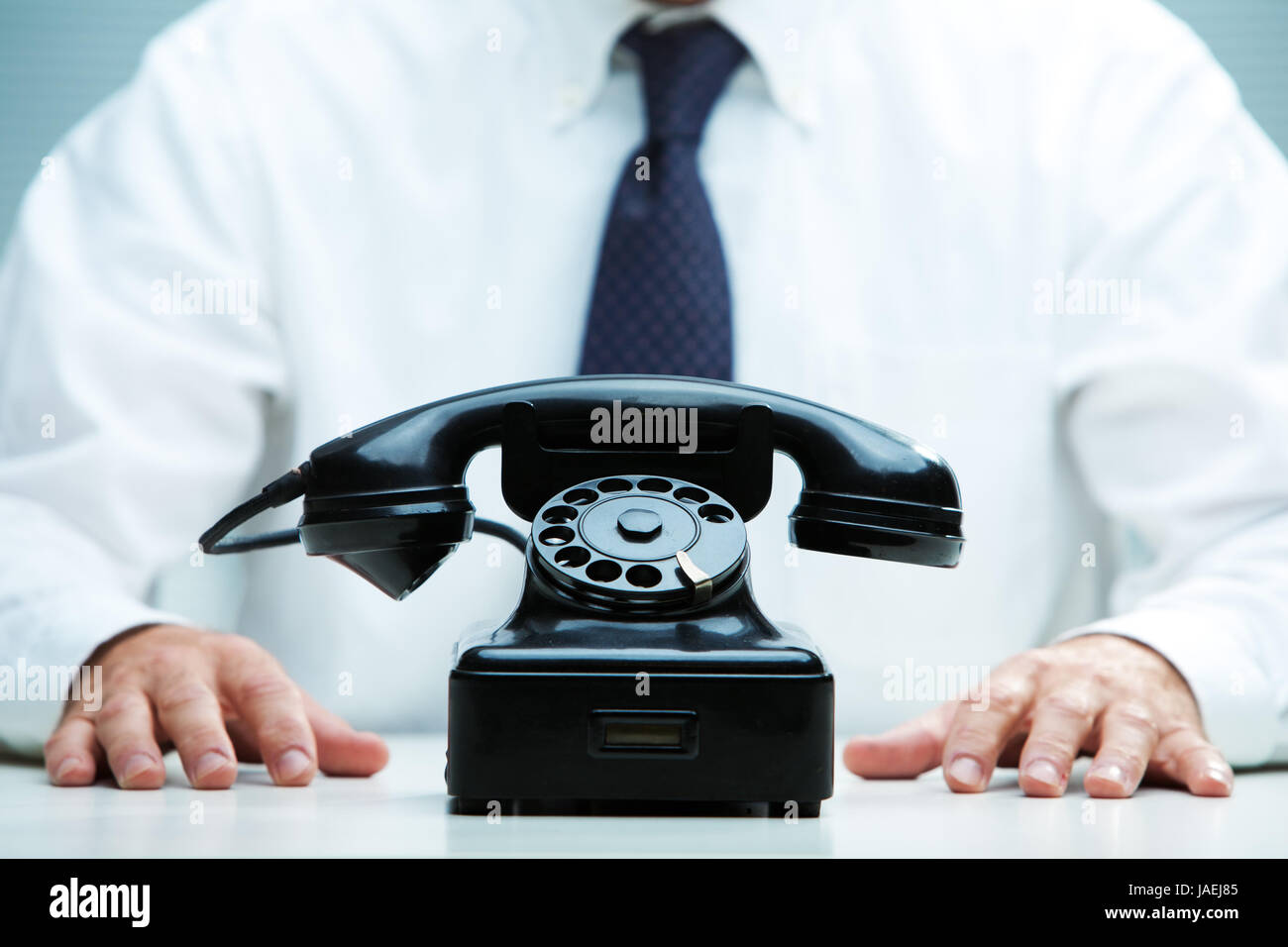 Telefono nero sul fuoco con un business in attesa di una chiamata sullo sfondo Foto Stock