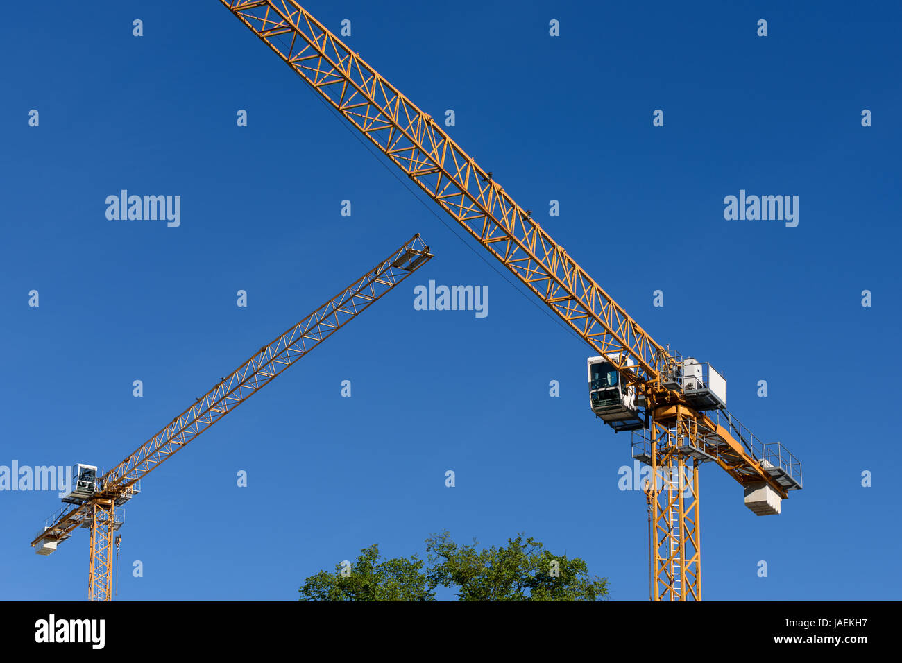 Due generici gru edili su un cielo blu sullo sfondo. Foto Stock