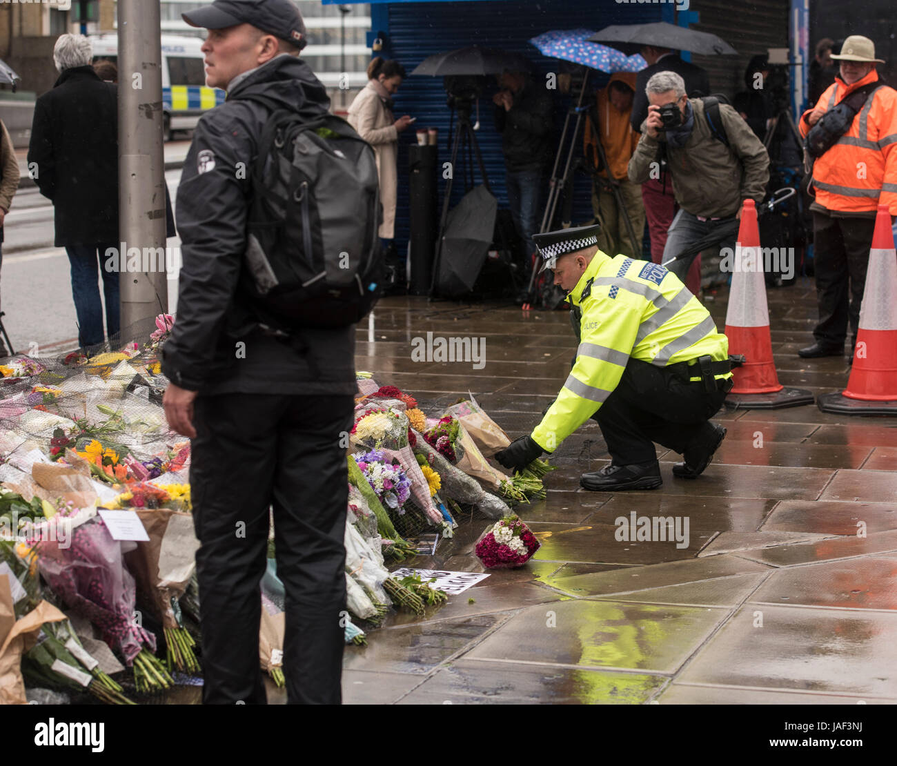 Londra, Regno Unito. Il 6 giugno, 2017. Un funzionario di polizia luoghi fiori presso il memoriale di fortuna, dopo gli attentati terroristici a Londra London Bridge, dopo i due minuti di silenzio Credito: Ian Davidson/Alamy Live News Foto Stock