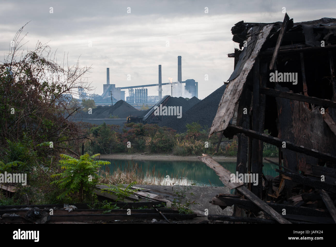 Guardando attraverso un parzialmente bruciato edificio lungo Jefferson Avenue a Detroit's Delray distretto, sull isola di Zugo e l impianto di produzione degli Stati Uniti Steel Corp. Pile di carbone, scoria e il coke di petrolio sono memorizzati scoperti lungo le rive dove il Fiume Detroit incontra il Rouge River. Foto Stock