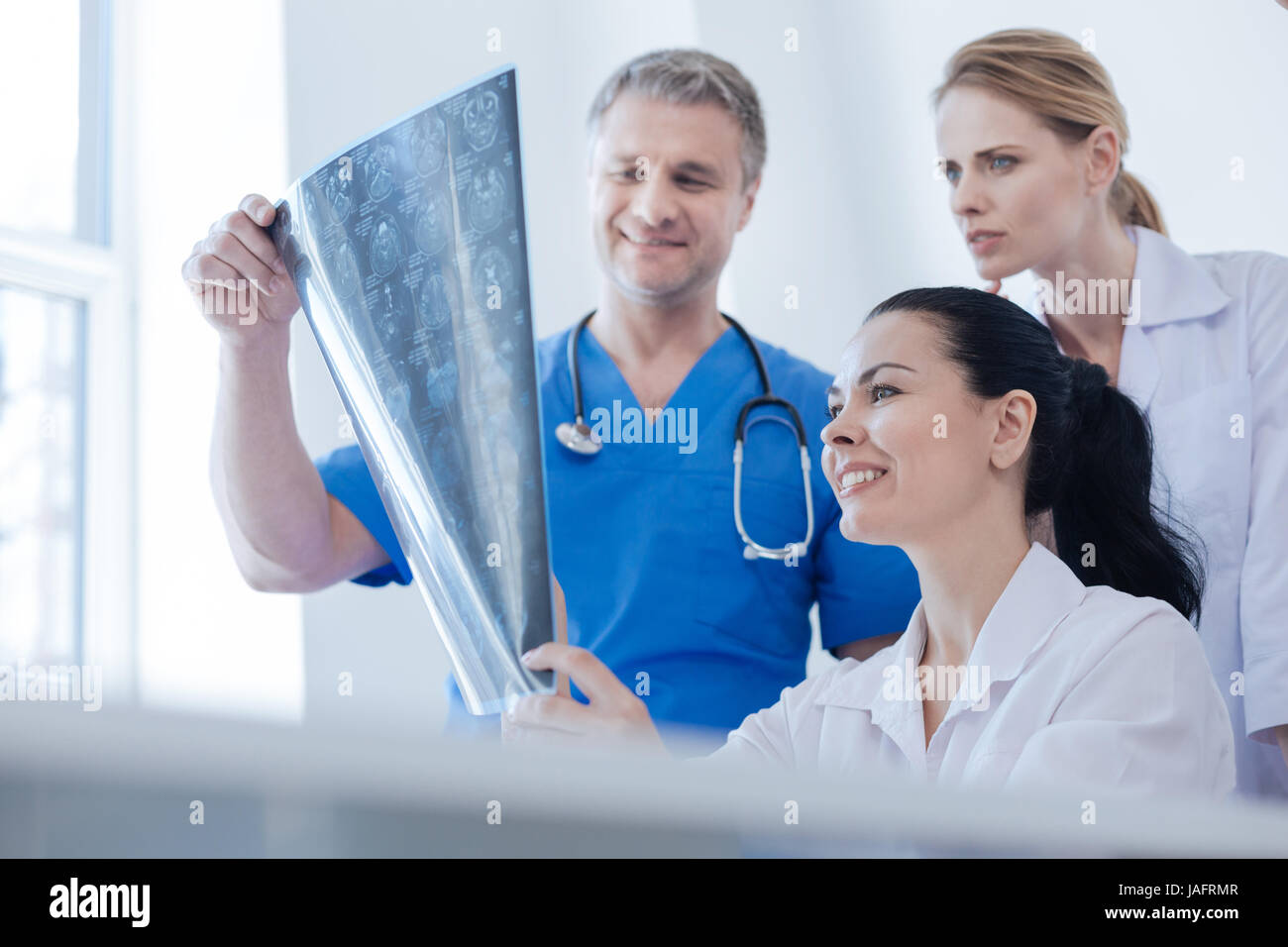 Atteggiamento professionale per i dettagli. Active proficient radiologi qualificati e di lavoro esaminando la scansione tc presso la clinica mentre godendo la conversazione e Foto Stock