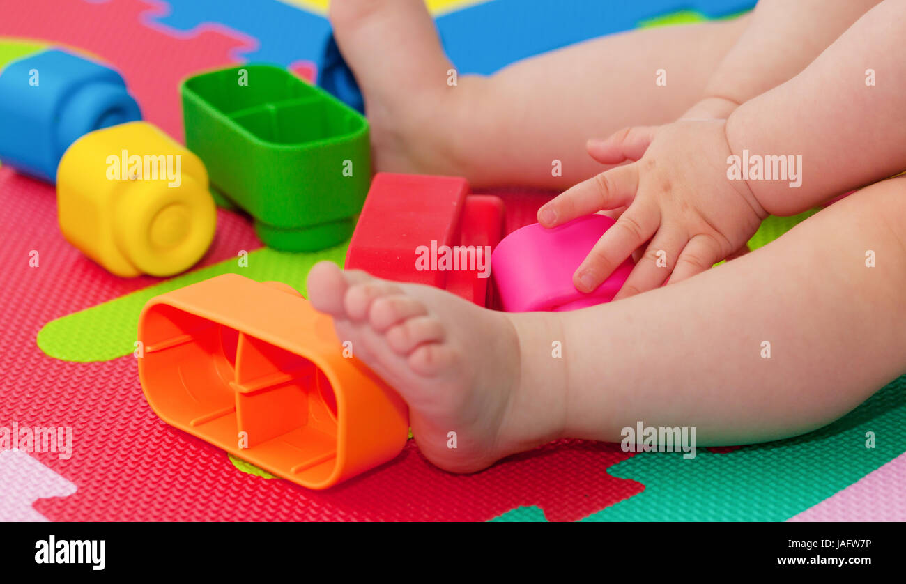Bambino gioca con blocchi di costruzione sul colorato tappetino di gomma. Foto Stock