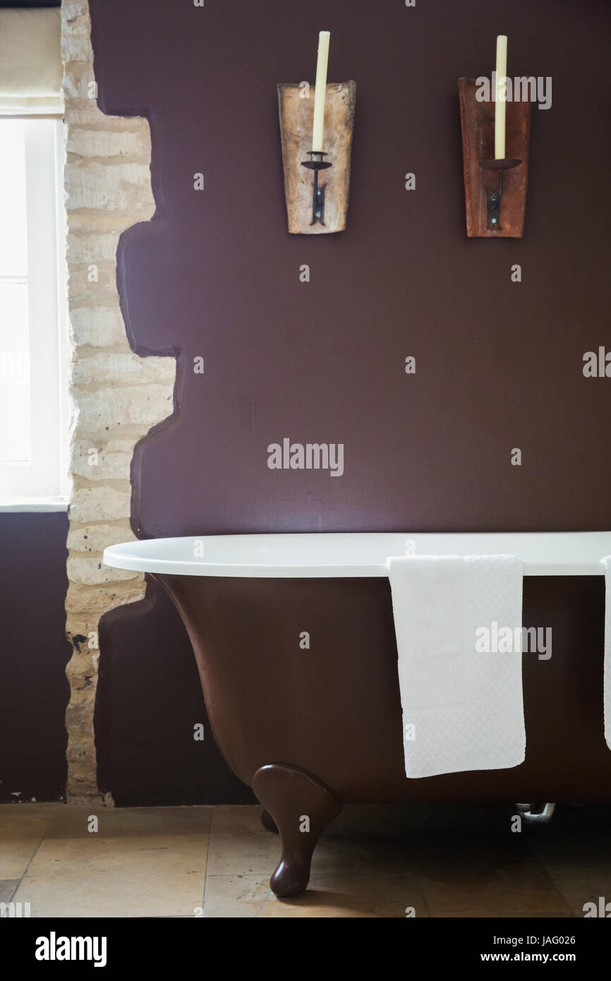 Vista interna di una stanza da bagno separata con vasca roll-top con viola pareti dipinte. Foto Stock